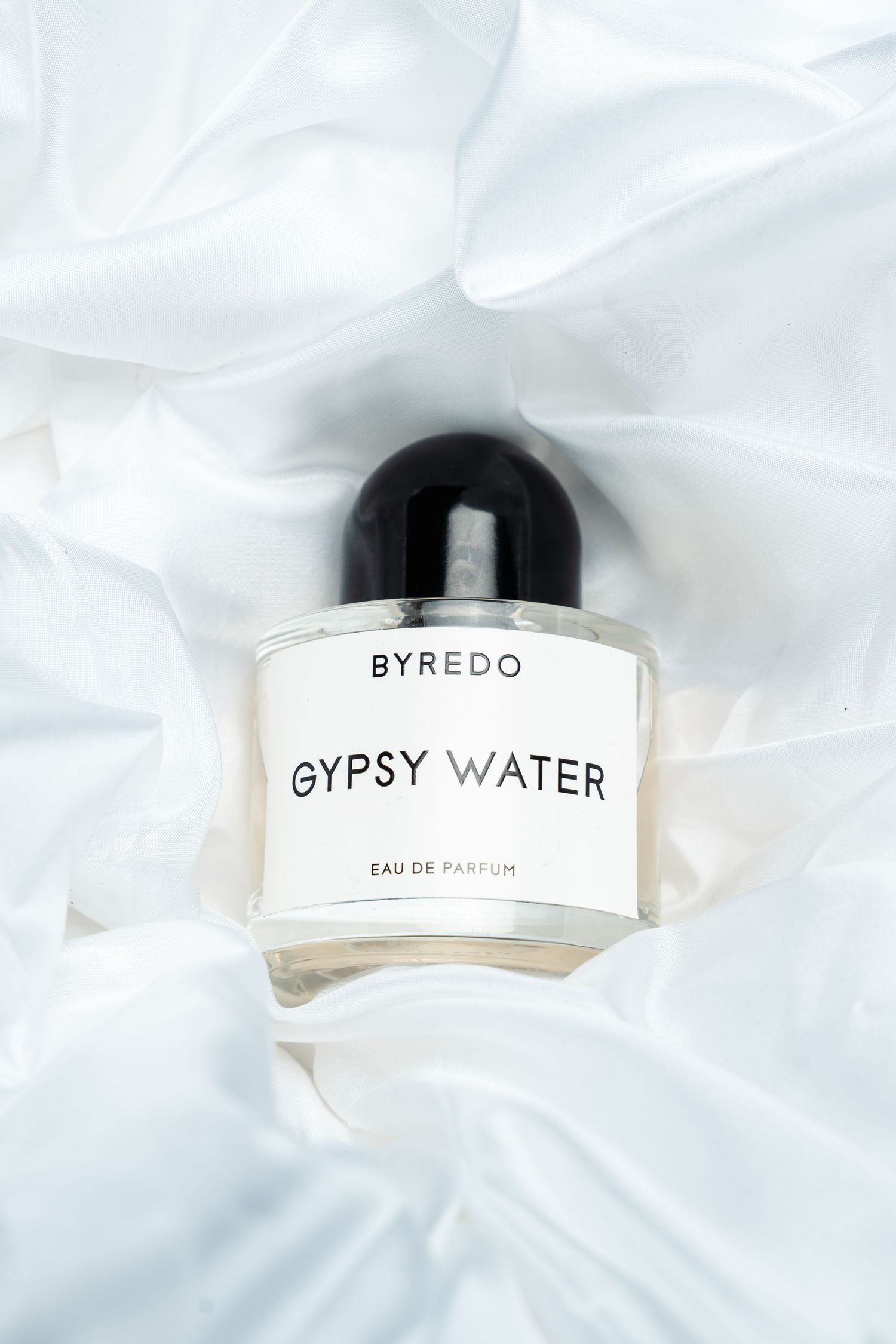Byredo Gypsy Water perfume bottle displayed on white silky fabric.