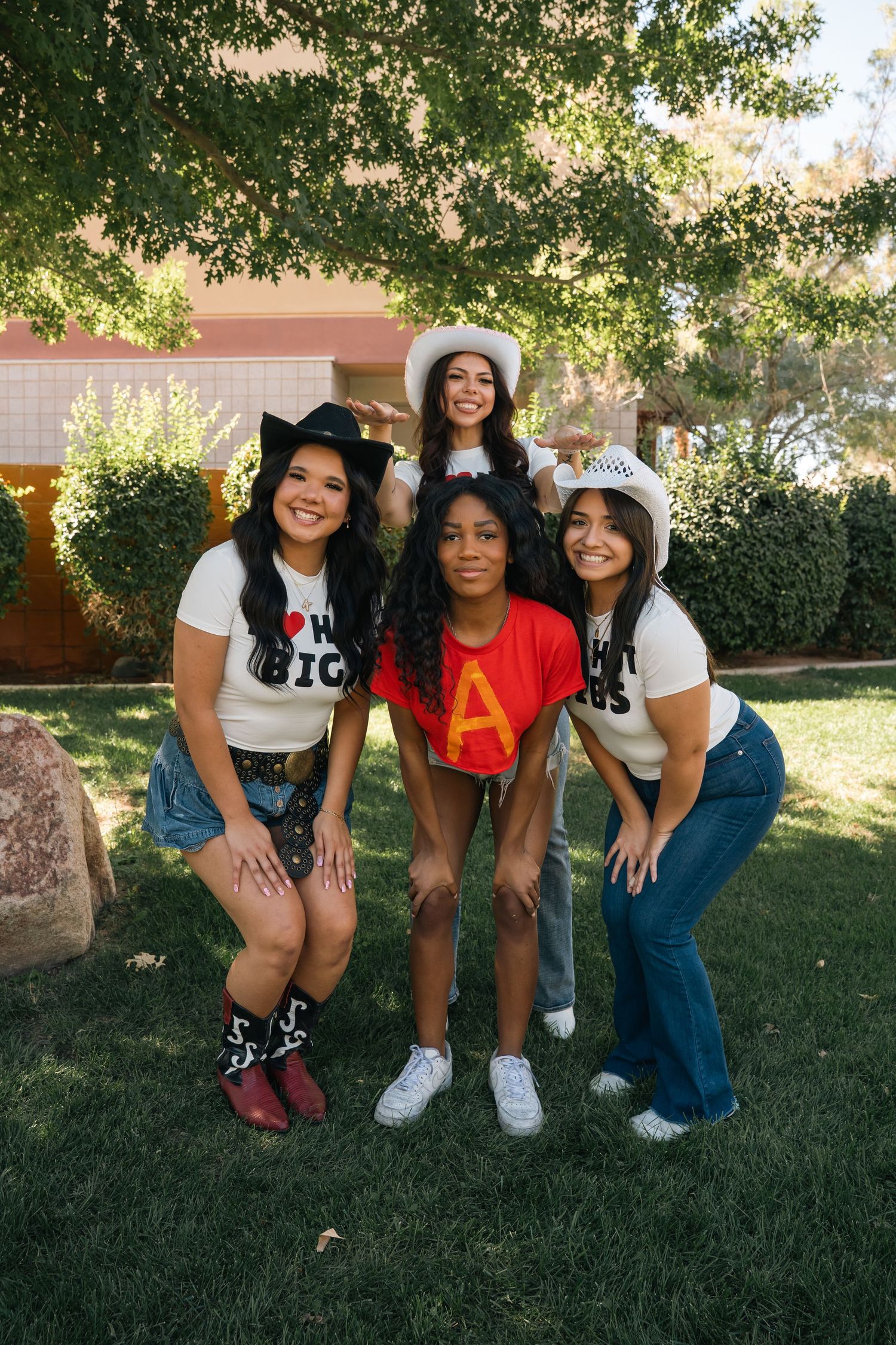 Group wearing matching t-shirts pose together on grass with decorative cat ears.