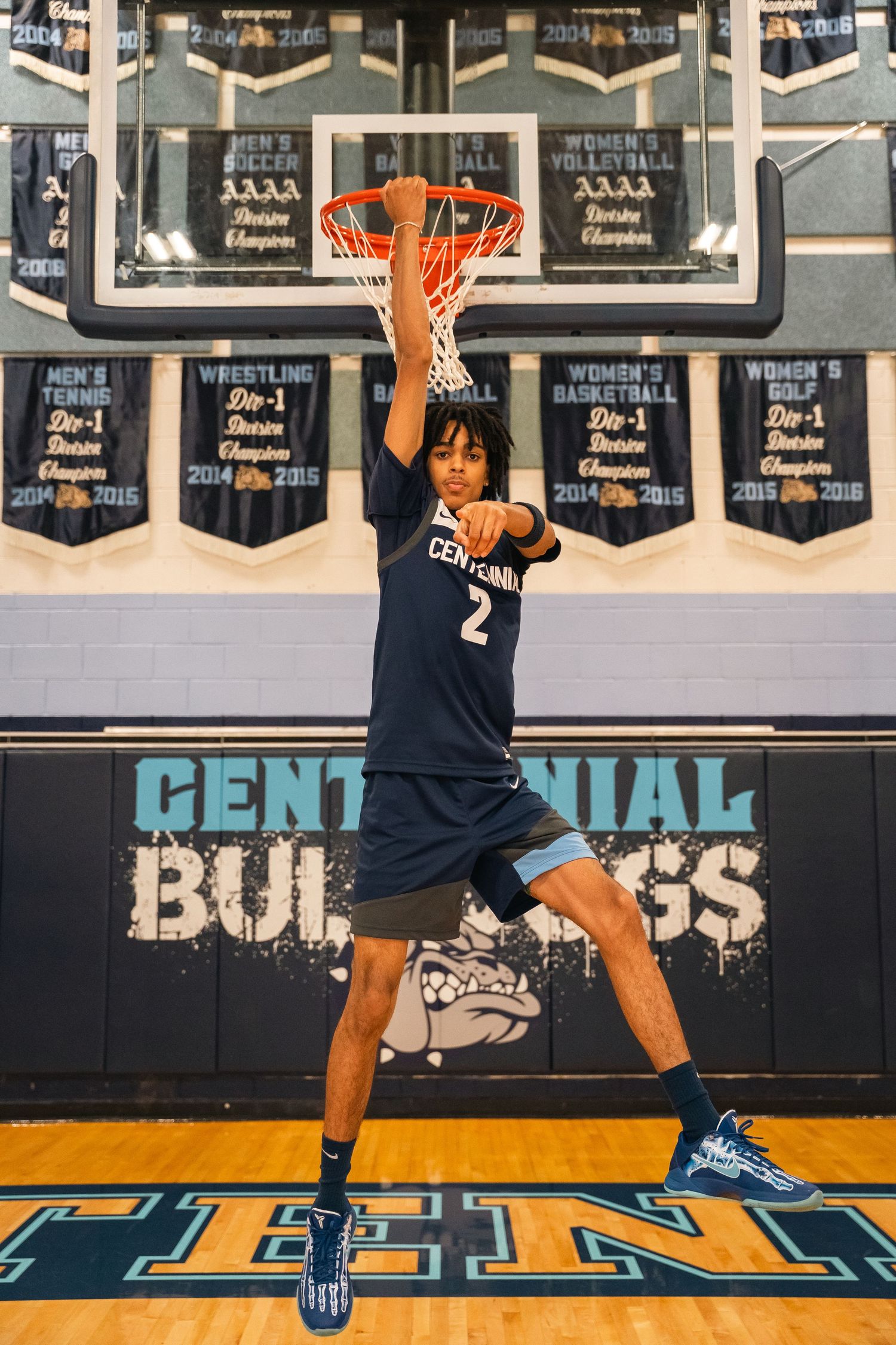 Basketball player in Centennial jersey dunks ball during photo shoot.