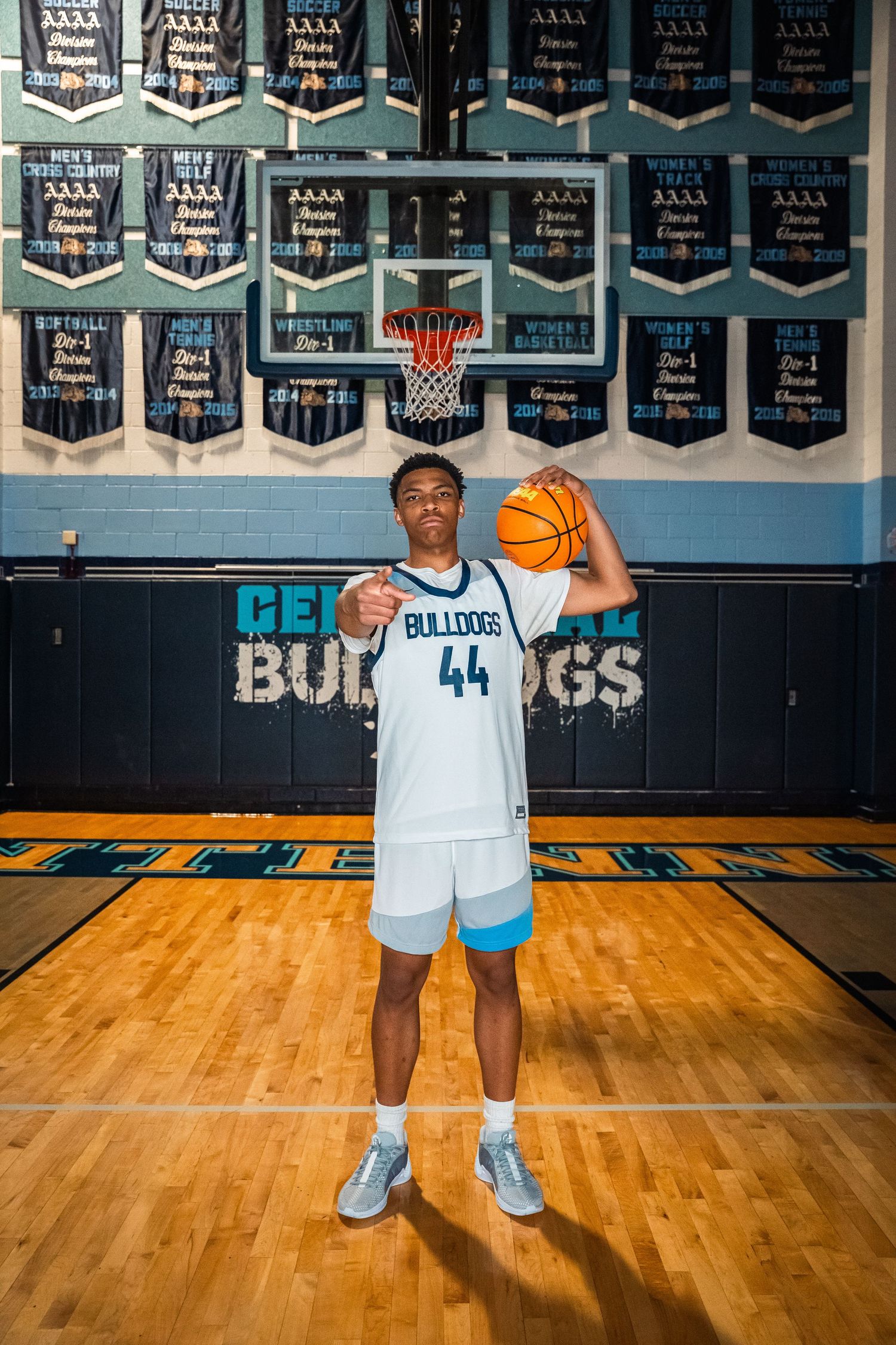 Basketball player in number 44 Bulldogs jersey holds ball while standing under team banners.