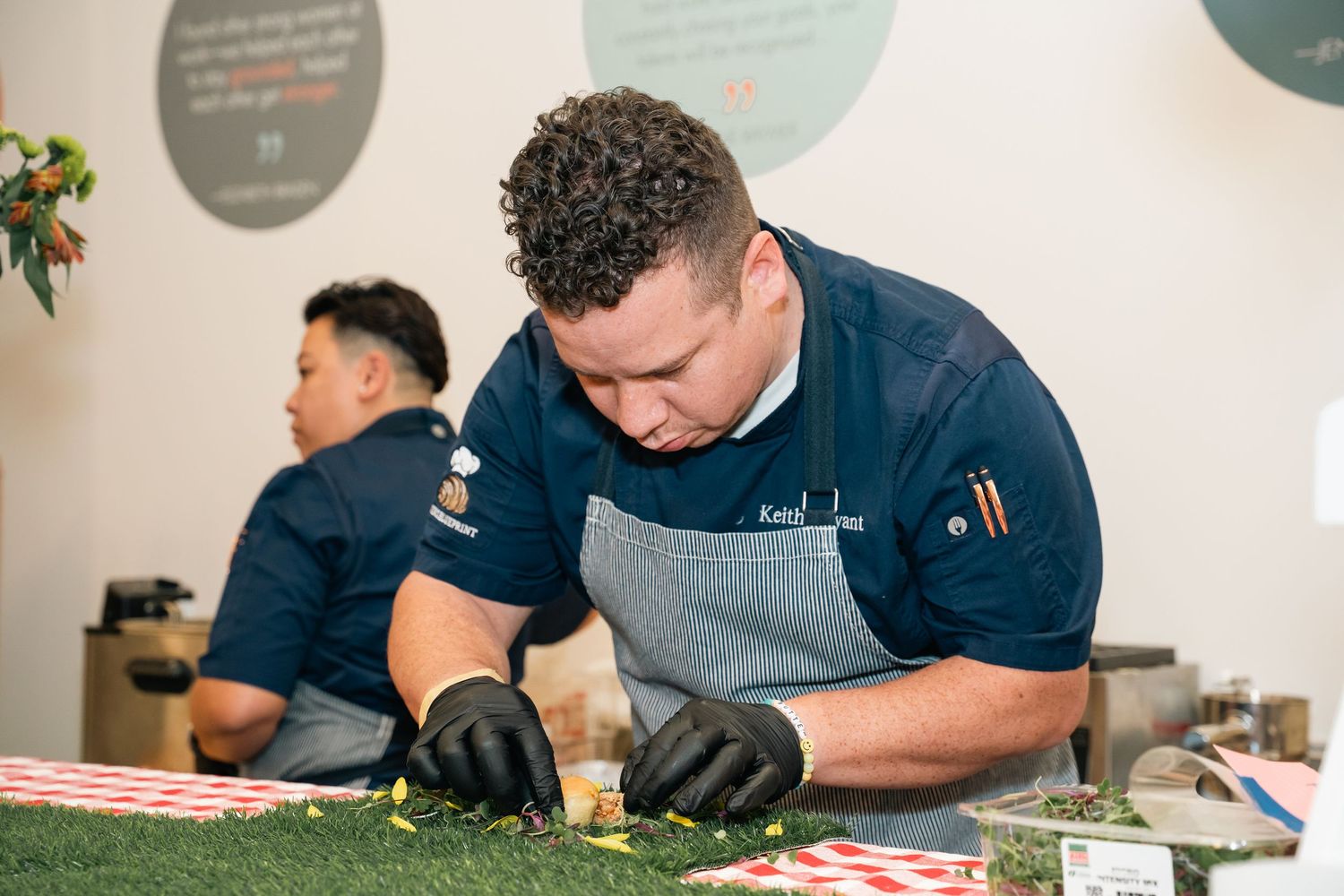 Chefs in dark uniforms preparing food at a culinary event.