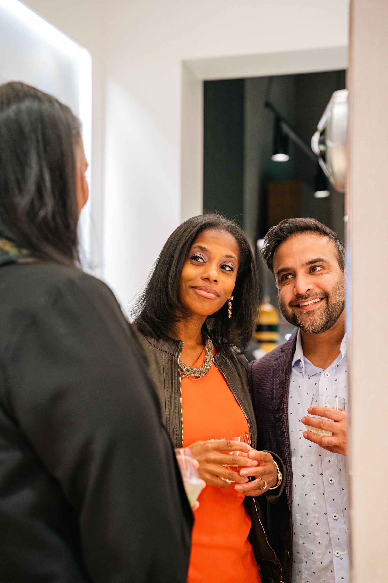 A couple sharing drinks and laughing together in a brightly lit modern space.