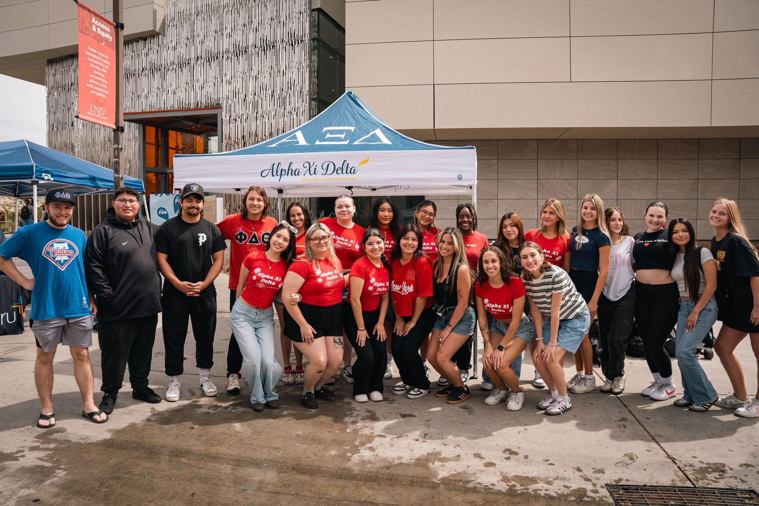 Large group of students in red and black shirts gather outside for a club event photo.