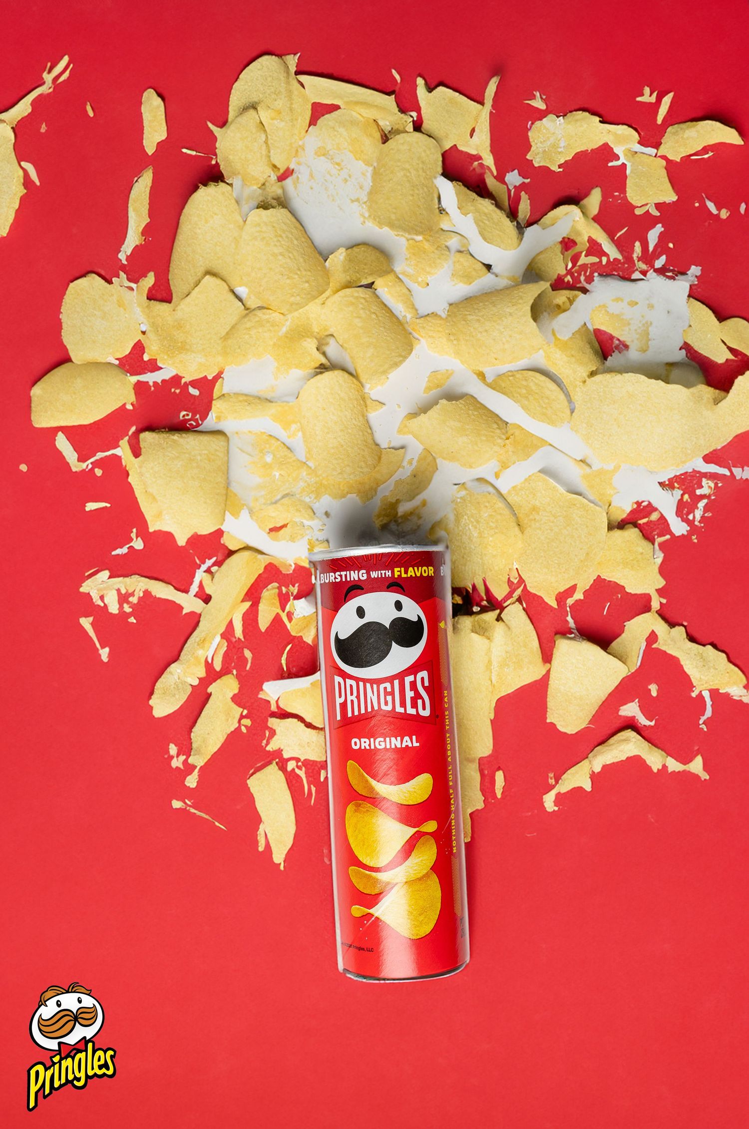 Exploding Pringles original chips around can on red background.