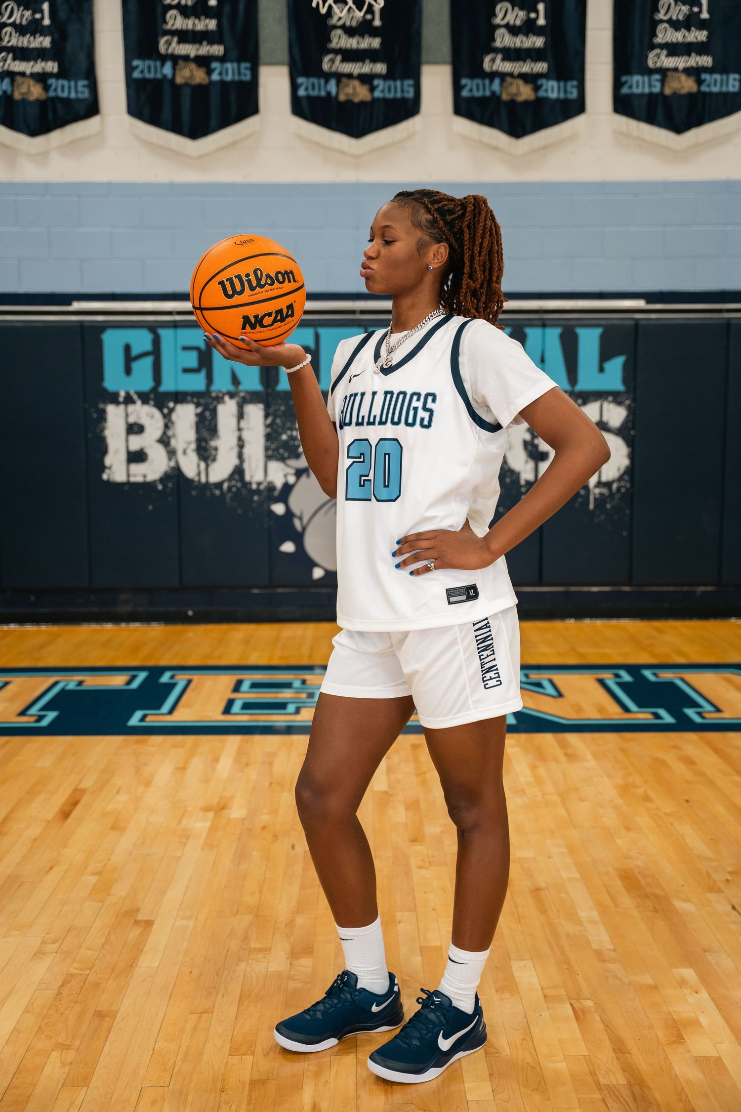 Basketball player in number 20 Bulldogs uniform poses with Wilson NCAA basketball on court.