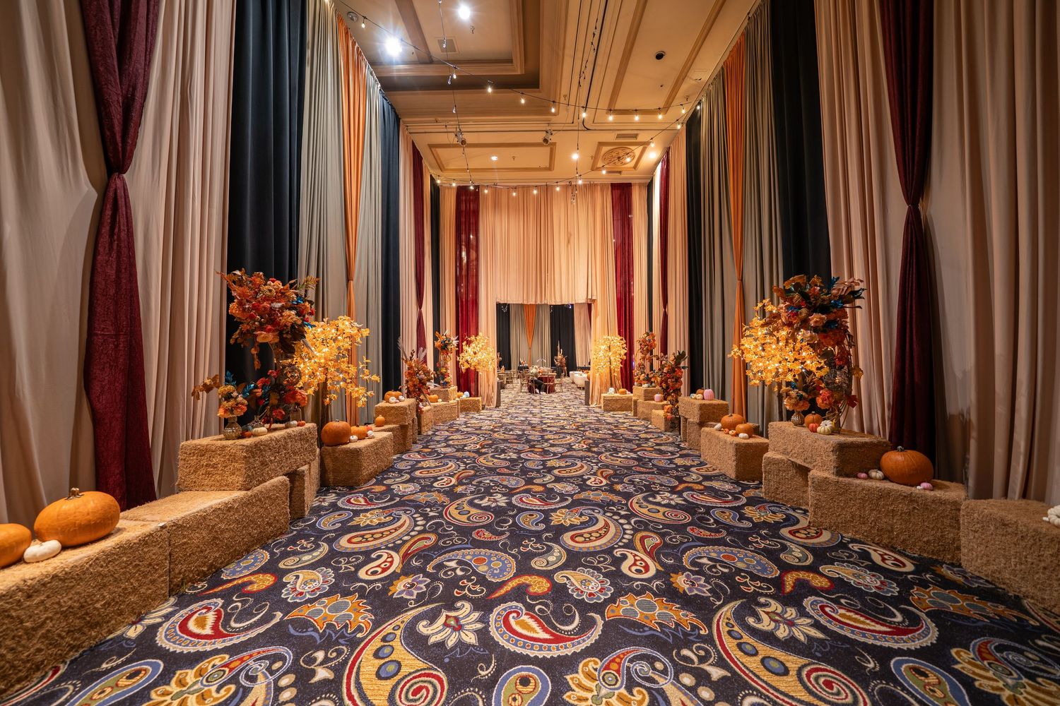Elegant carpeted hallway with draped curtains and autumn decorations in a casino setting.