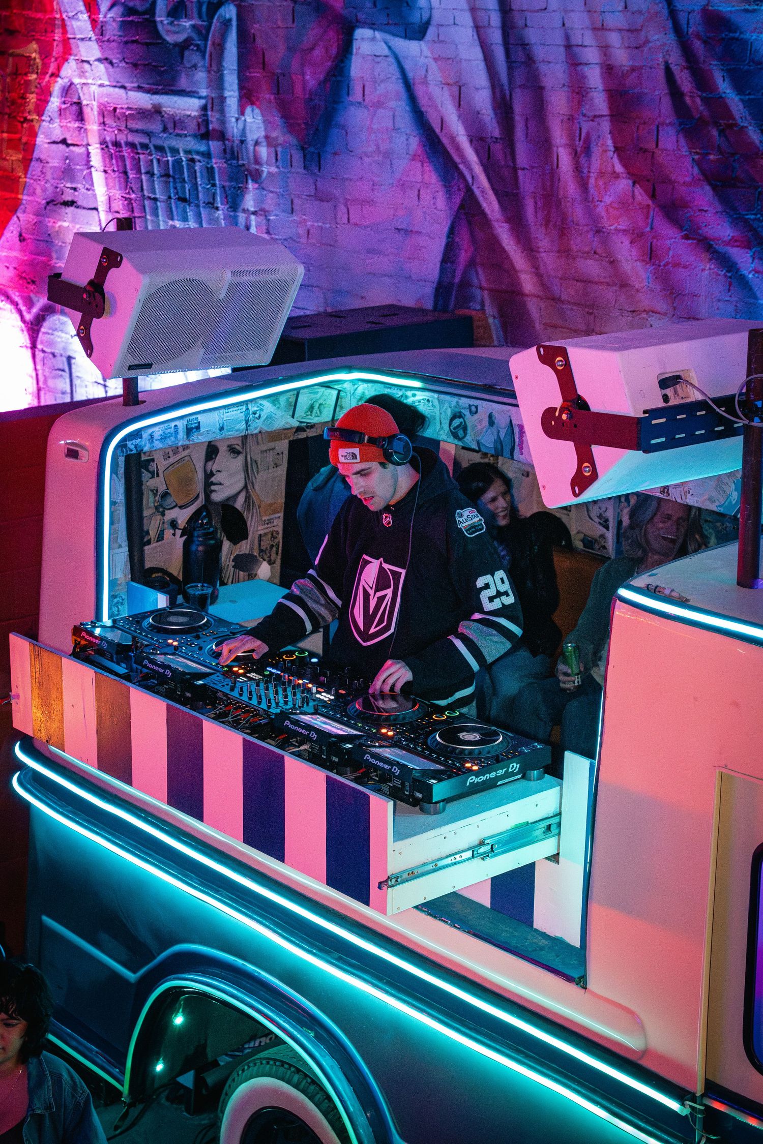 DJ performing in illuminated retro-styled booth with Vegas Golden Knights jersey.