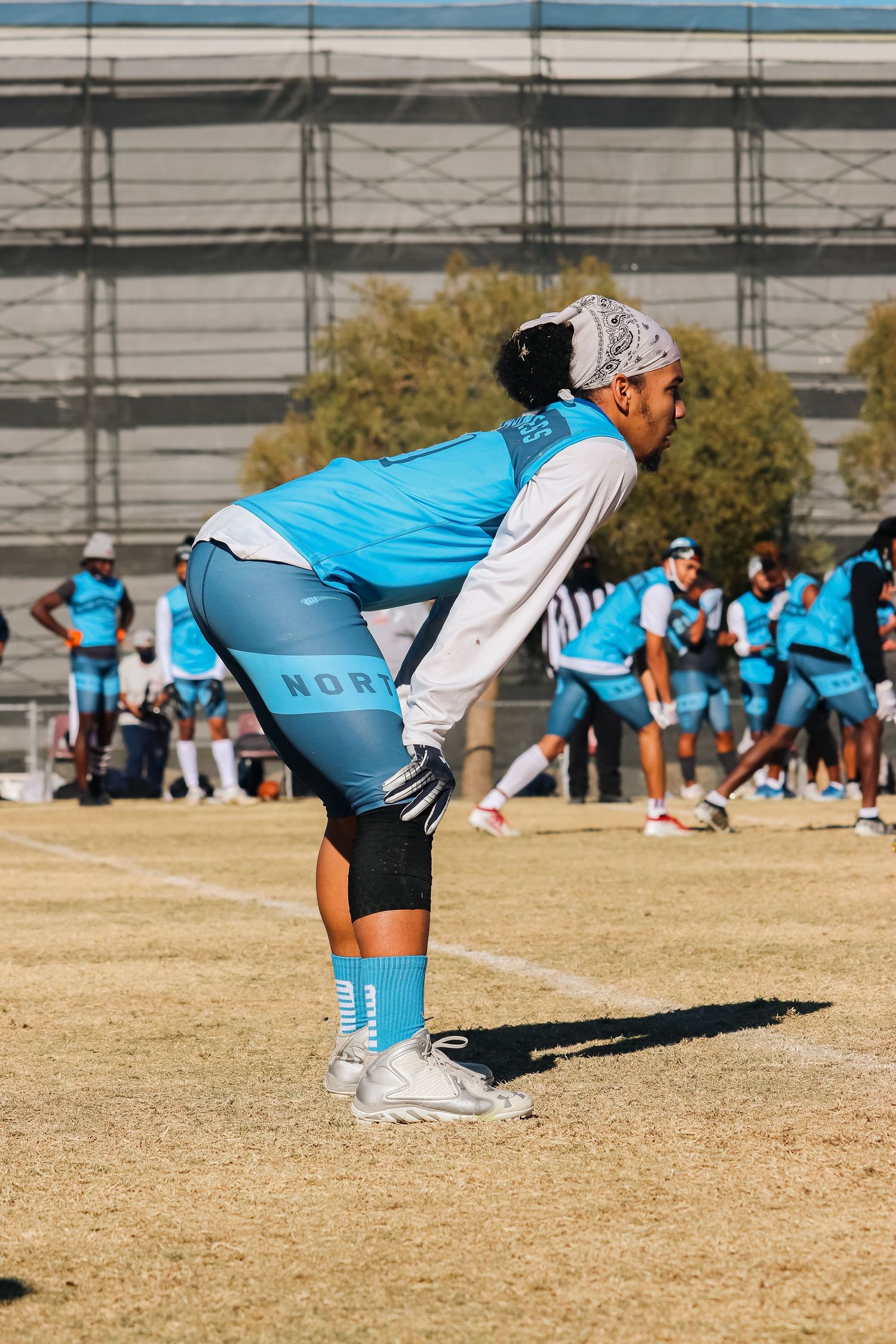 Athletes in blue uniforms performing stretching exercises in formation on a grass field.