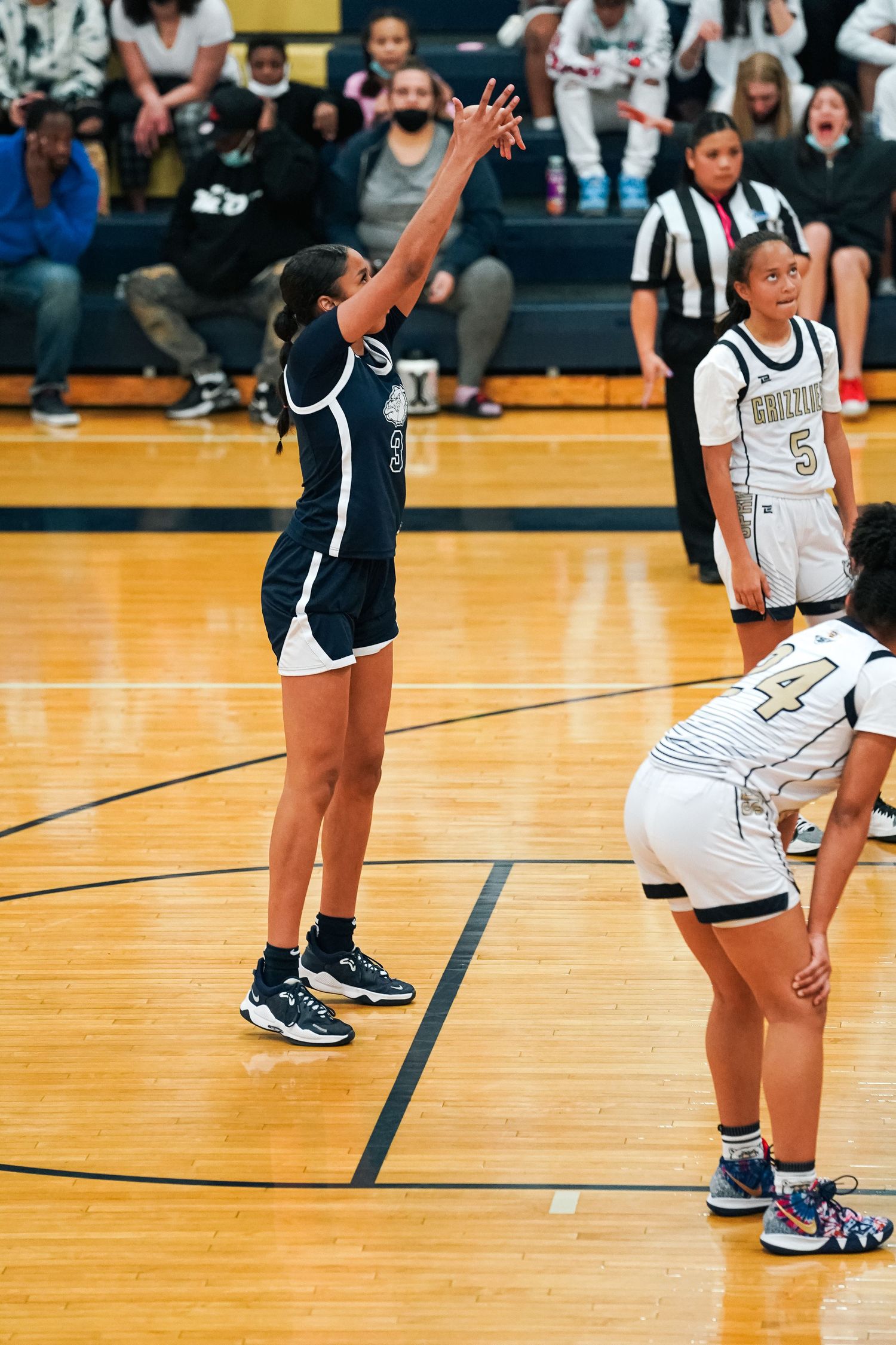 Players' feet and legs visible on a polished basketball court during gameplay.