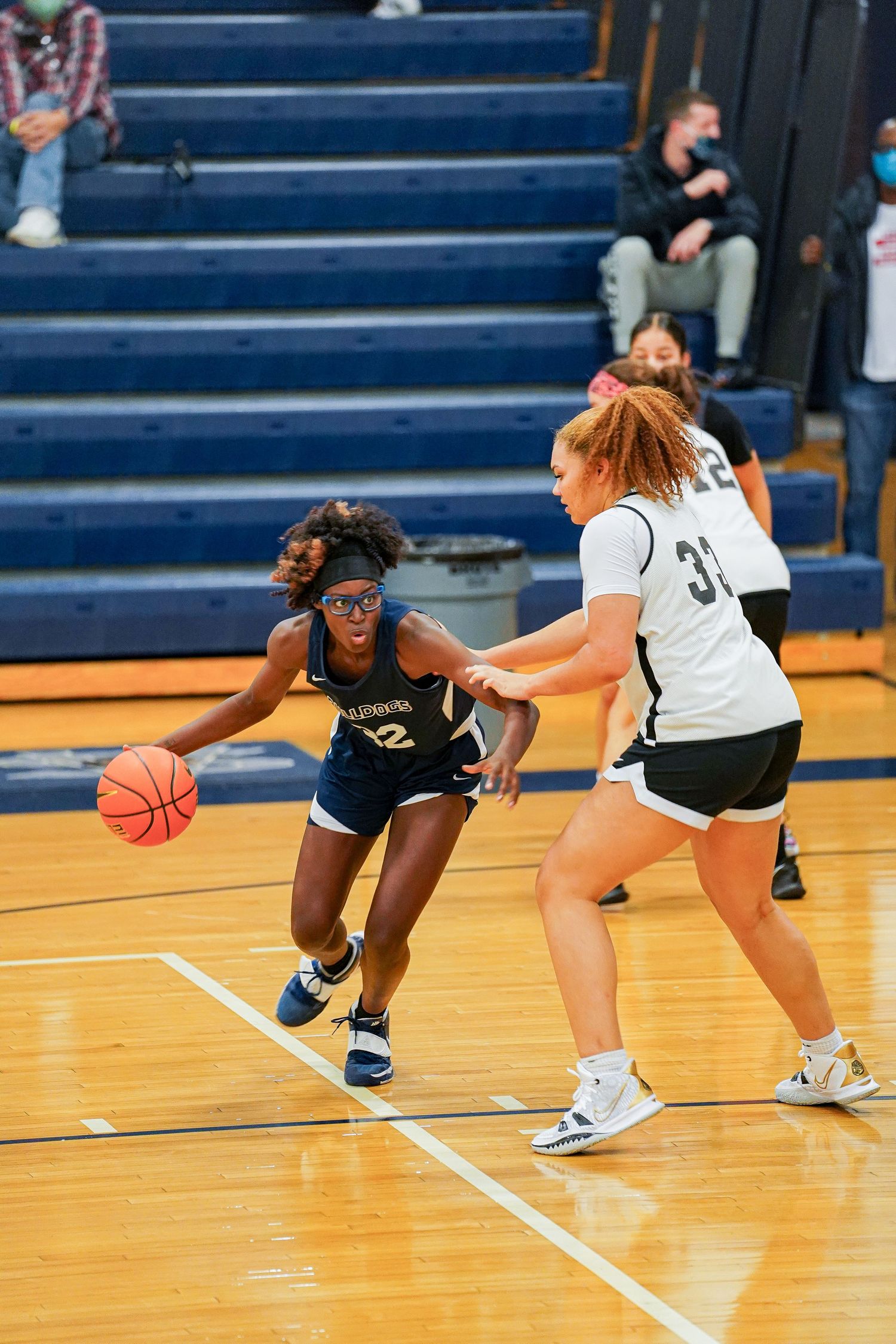 Basketball players dive for a loose ball during a fast-paced game on the hardwood court.
