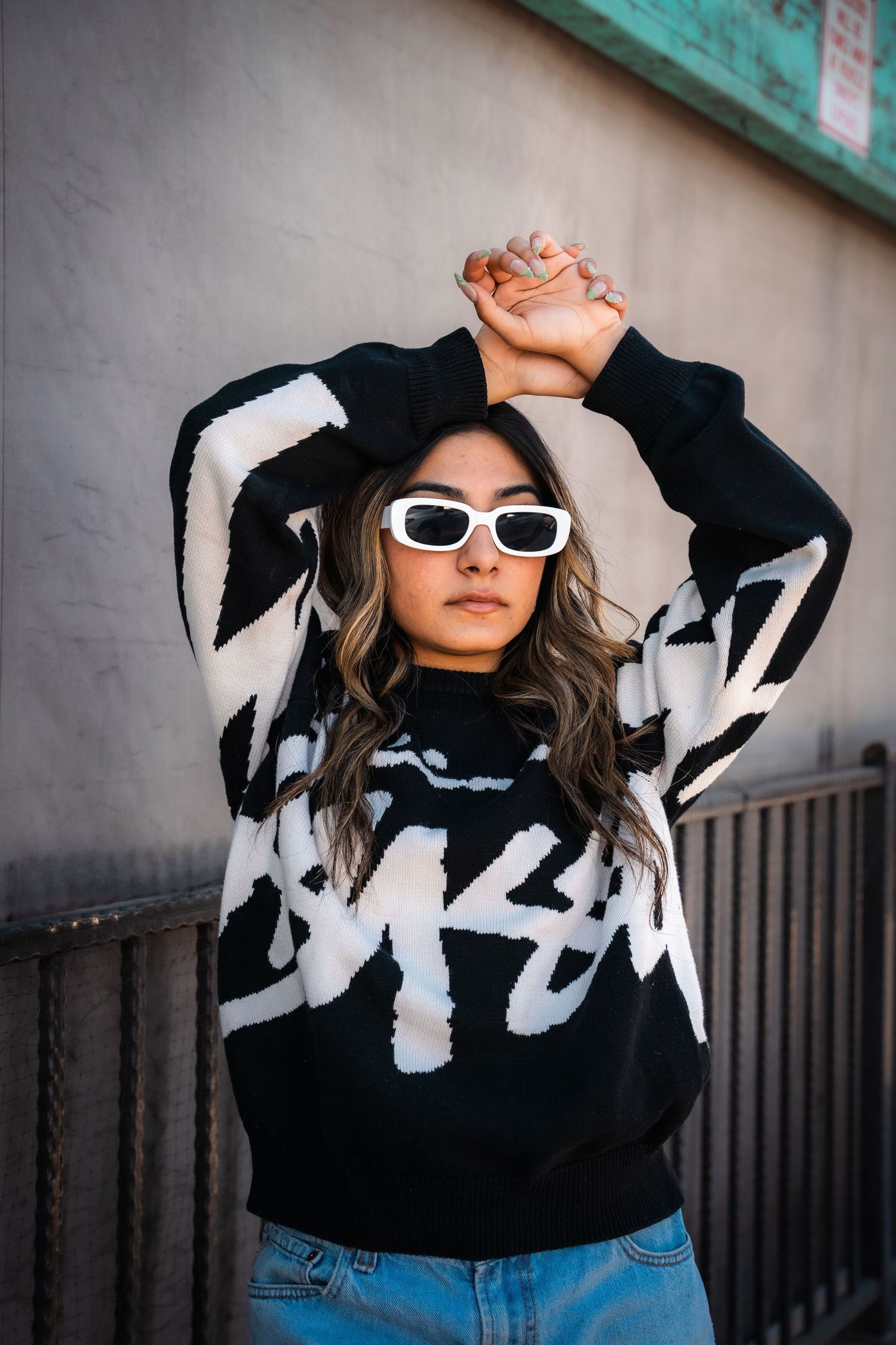 Fashion photos showing black and white patterned sweater with sunglasses against urban backdrop.