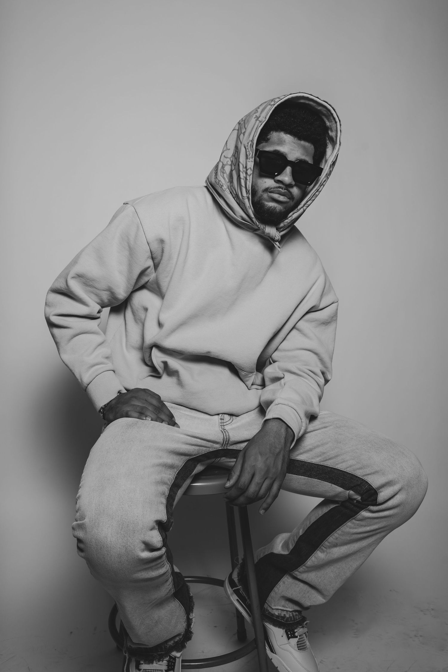 Person wearing a light colored hoodie captured in minimalist black and white photography.