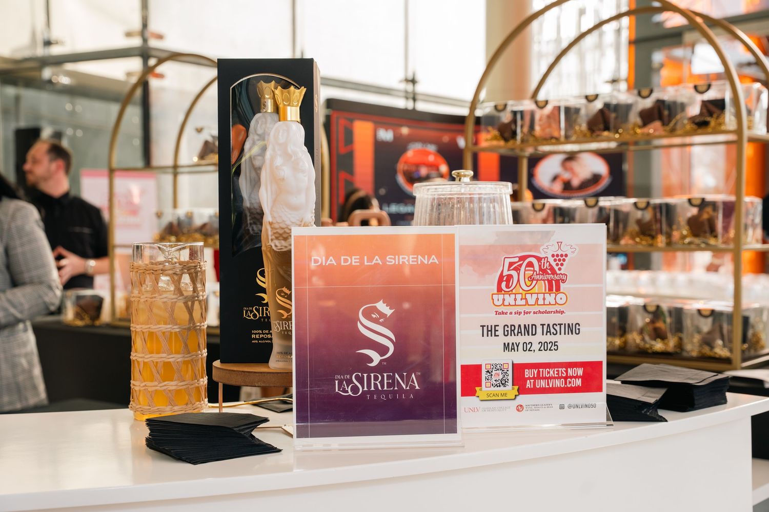 Bar setup displaying branded signage and beverage bottles at hospitality event.