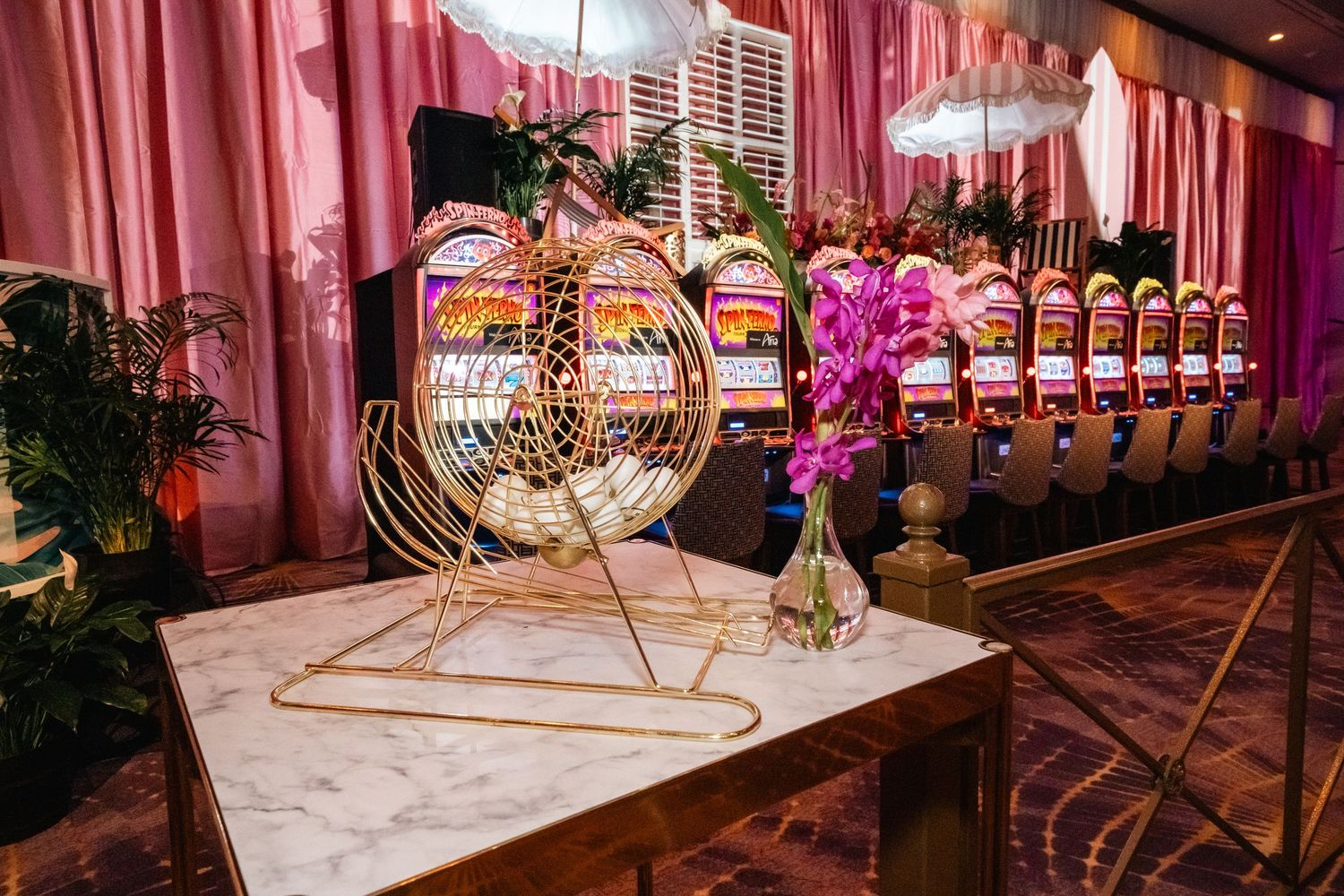Elegant bar display with decorative gold circular elements and pink orchids against draped fabric.