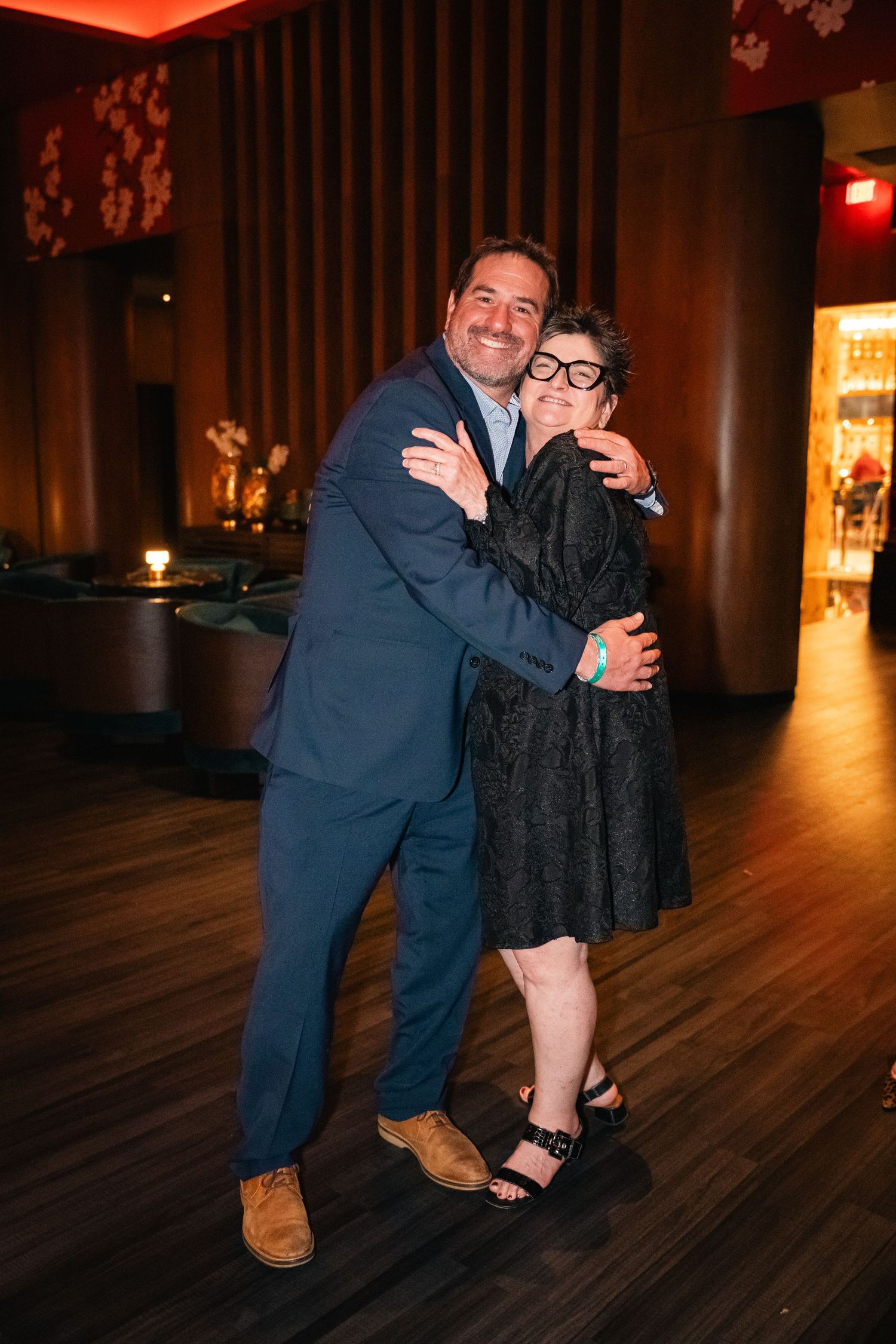 A couple sharing a warm embrace at an elegant evening event with mood lighting.