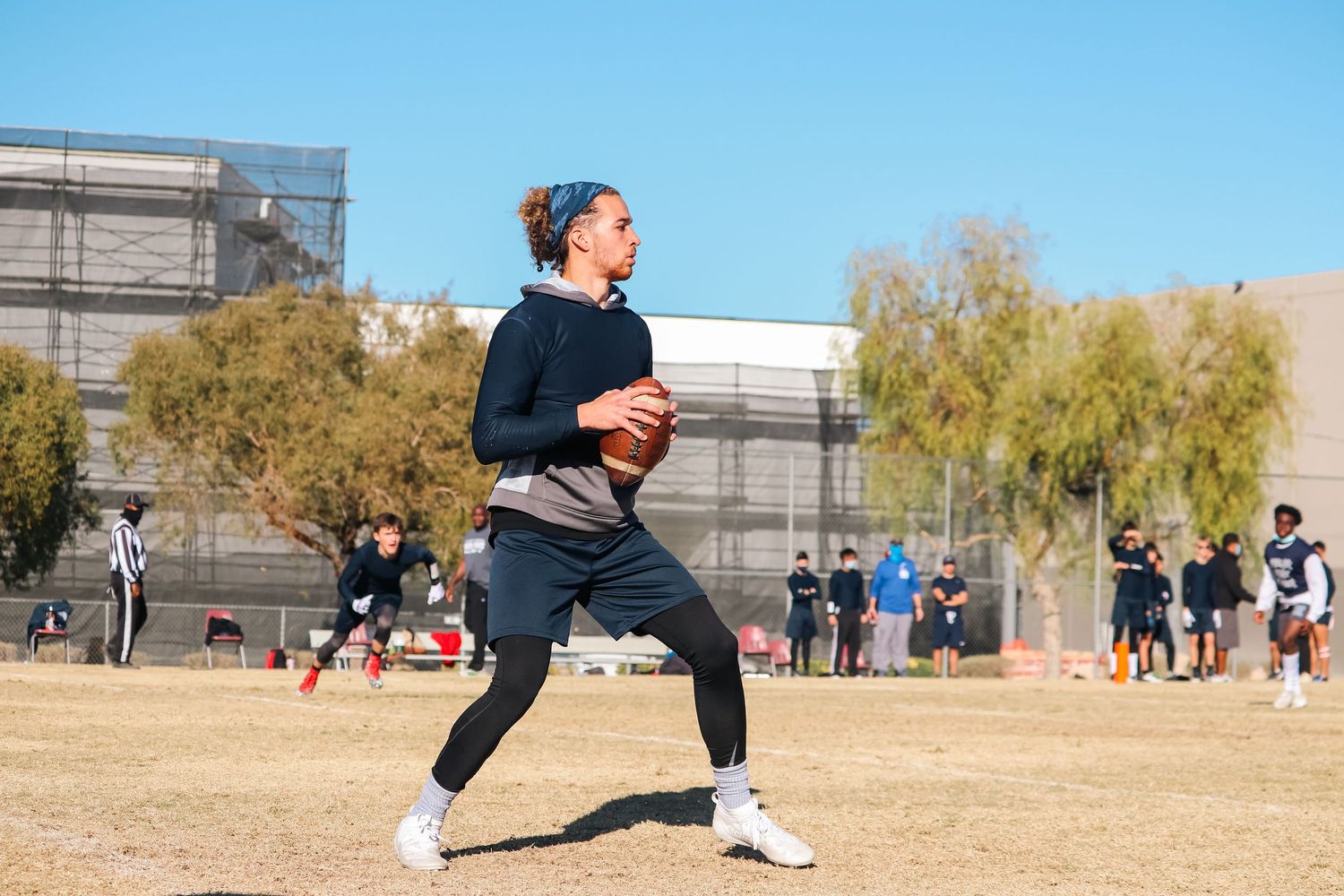 Player in dark athletic wear running with football during practice drill.