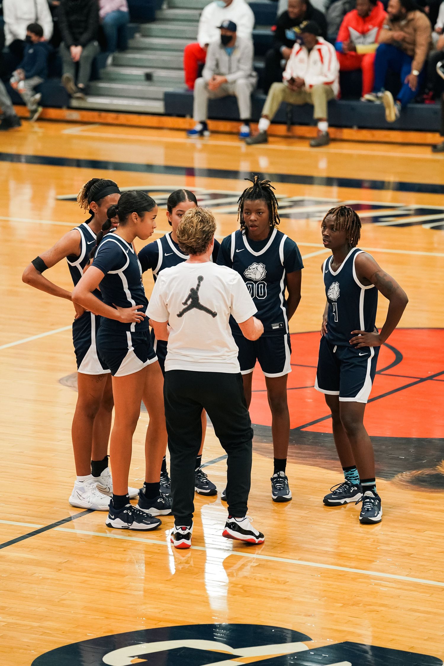 Athletes kneel on basketball court during pre-game activities.