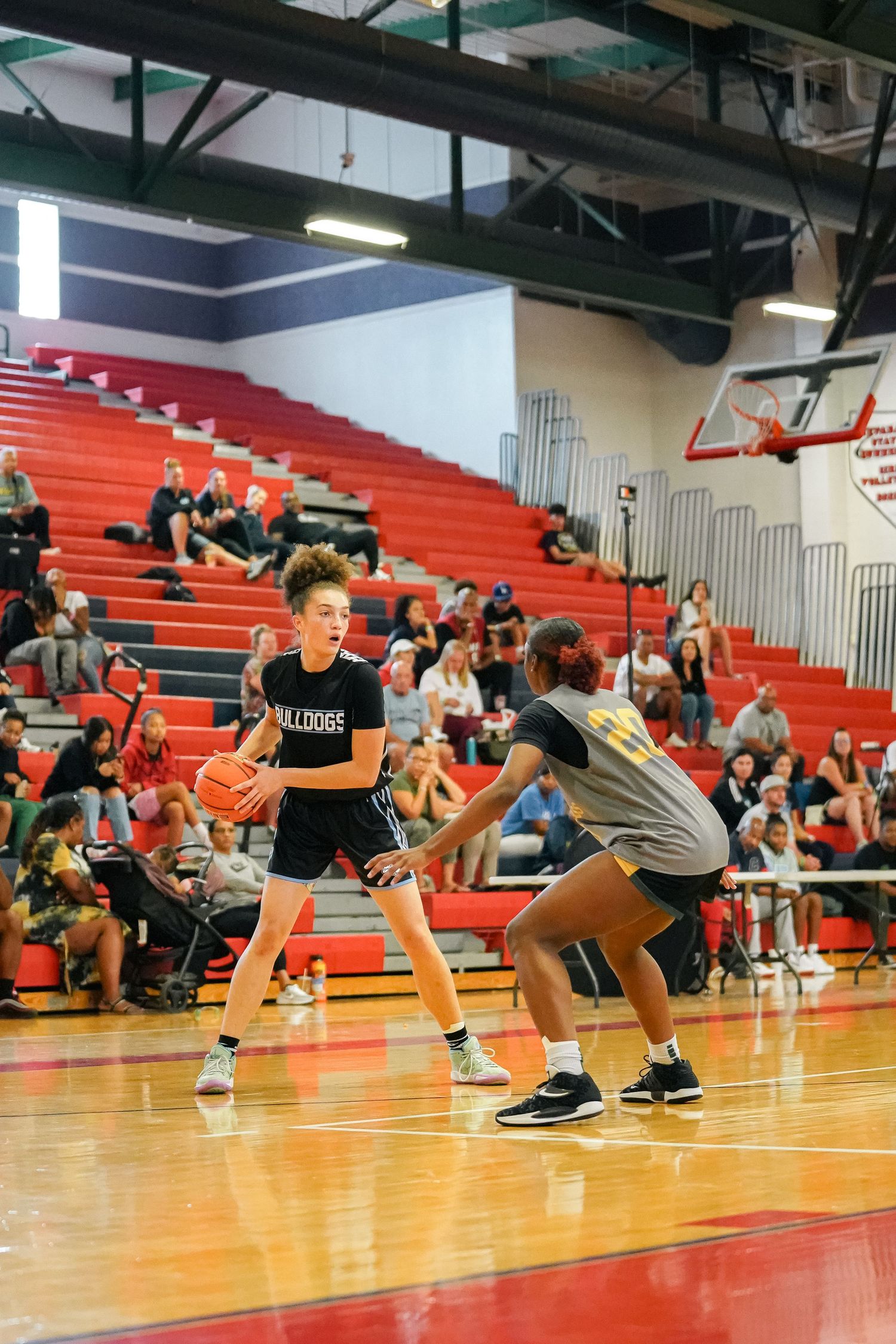 Two basketball players face off during intense game play on red court.