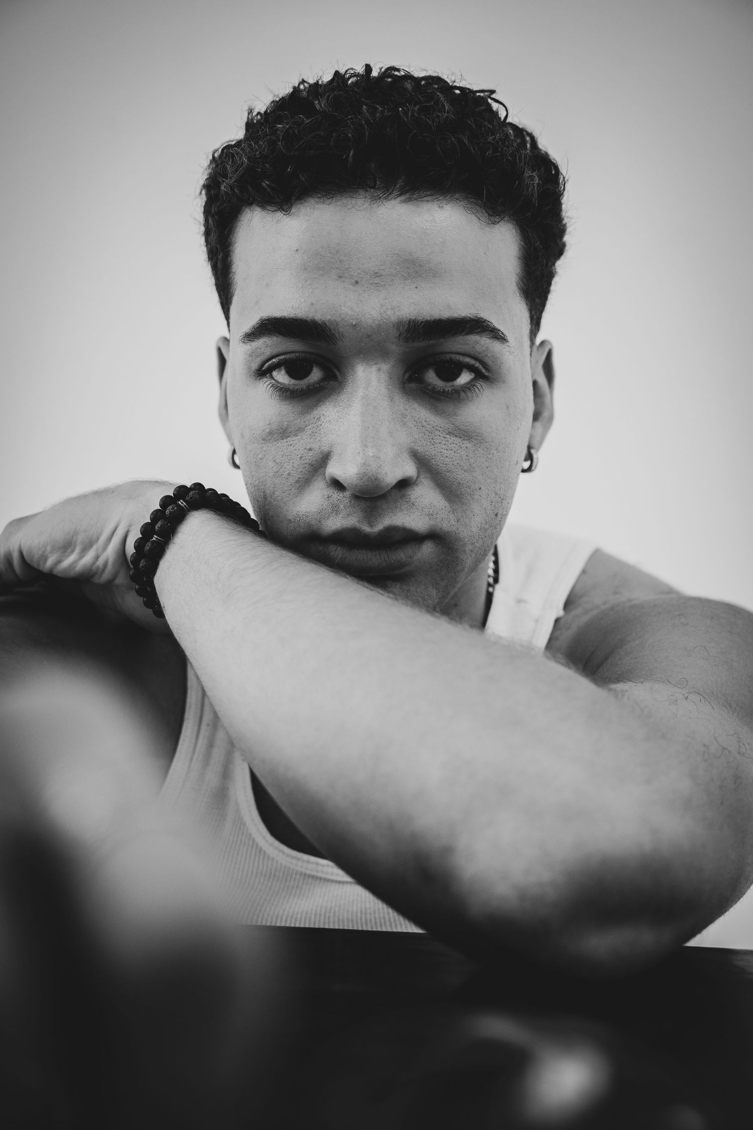 Intimate black and white portrait study showing person with arm covering part of their face.