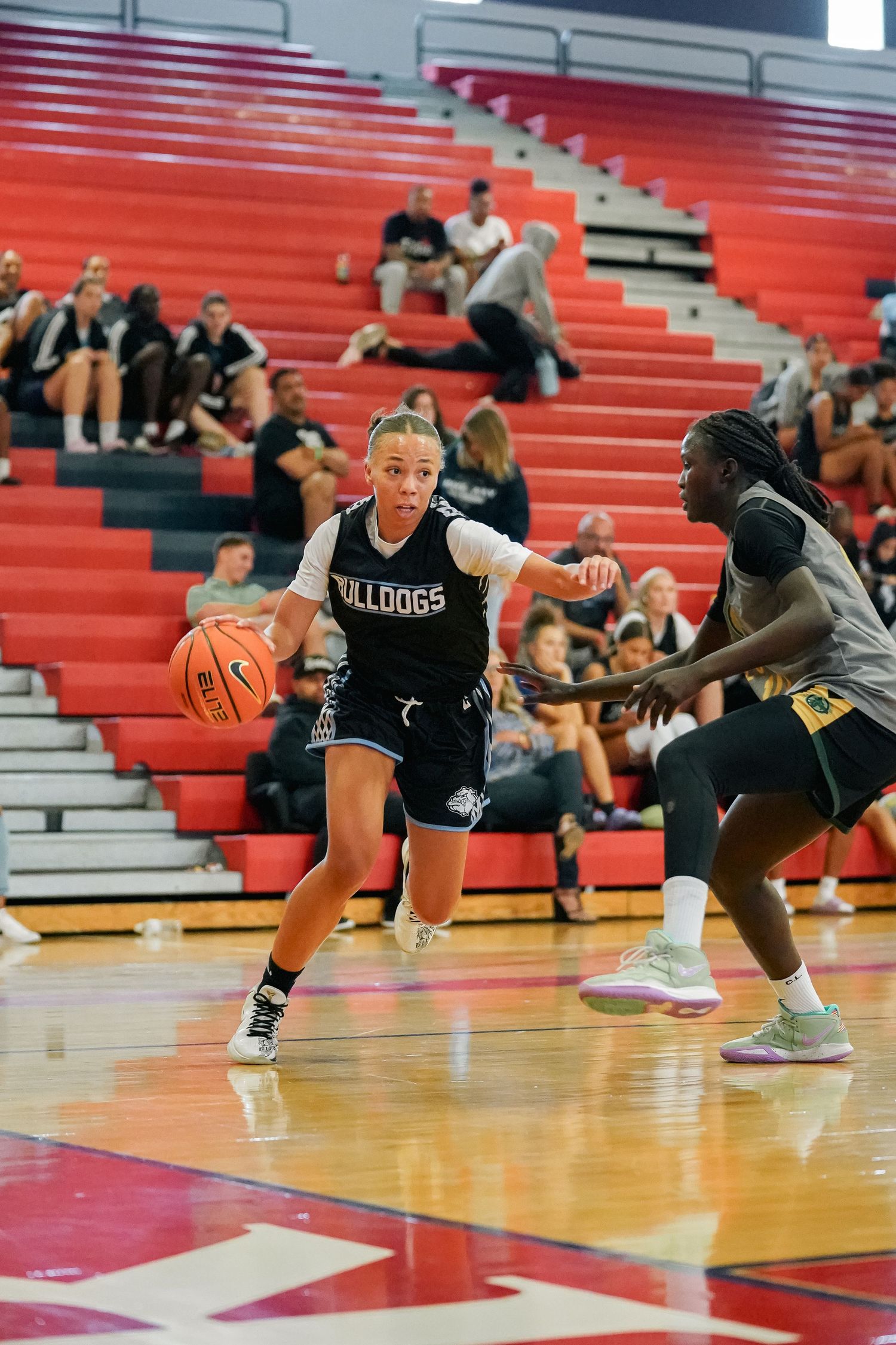 Athletes compete for ball possession during intense basketball game on indoor court.