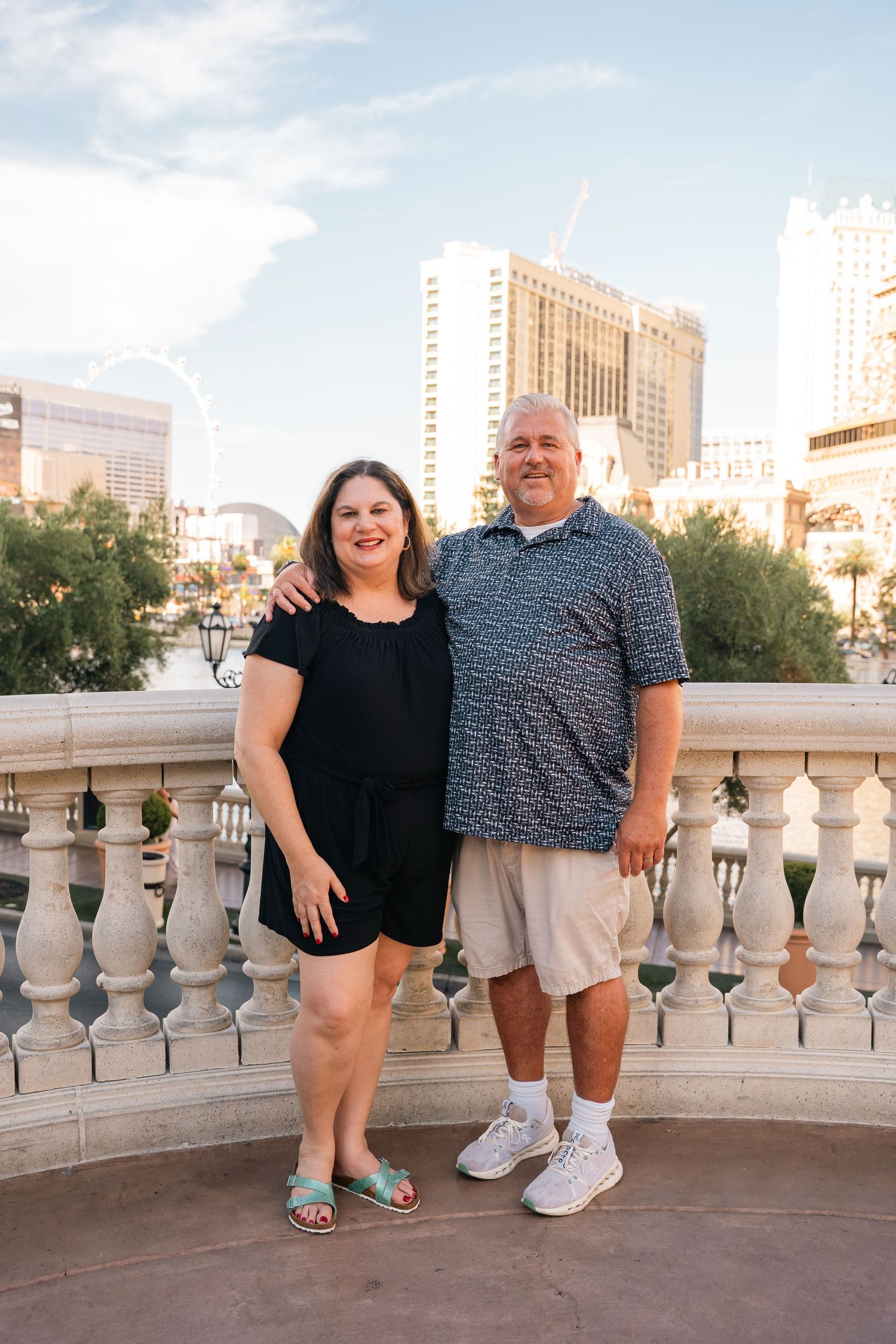Casual outdoor portraits against stone balustrade with Las Vegas cityscape in background.