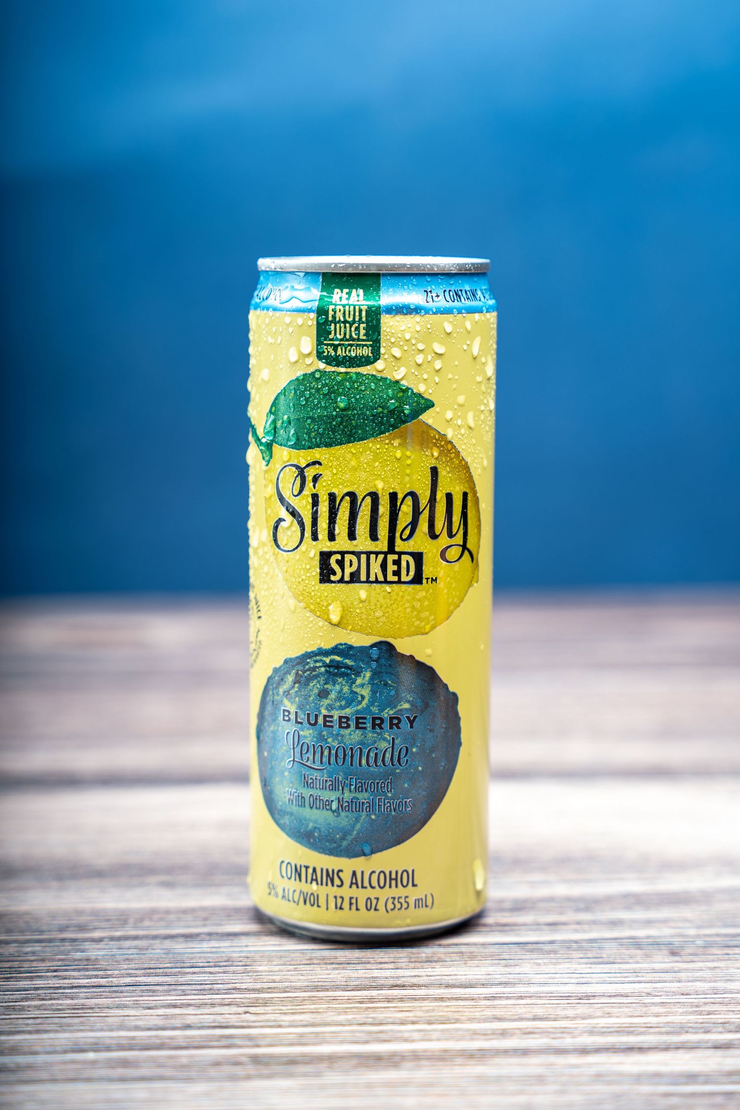 Can of Simply Spiked Blueberry Lemonade alcoholic beverage against blue background.