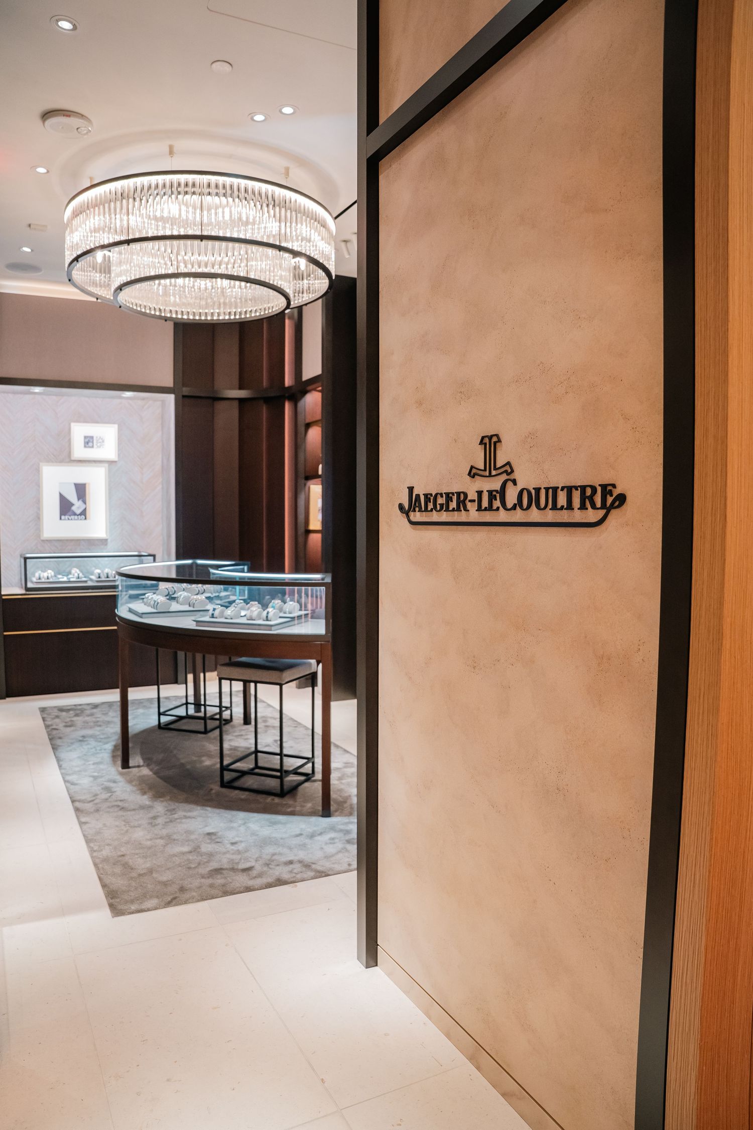 Jaeger-LeCoultre boutique interior with beige walls and illuminated glass display cases.