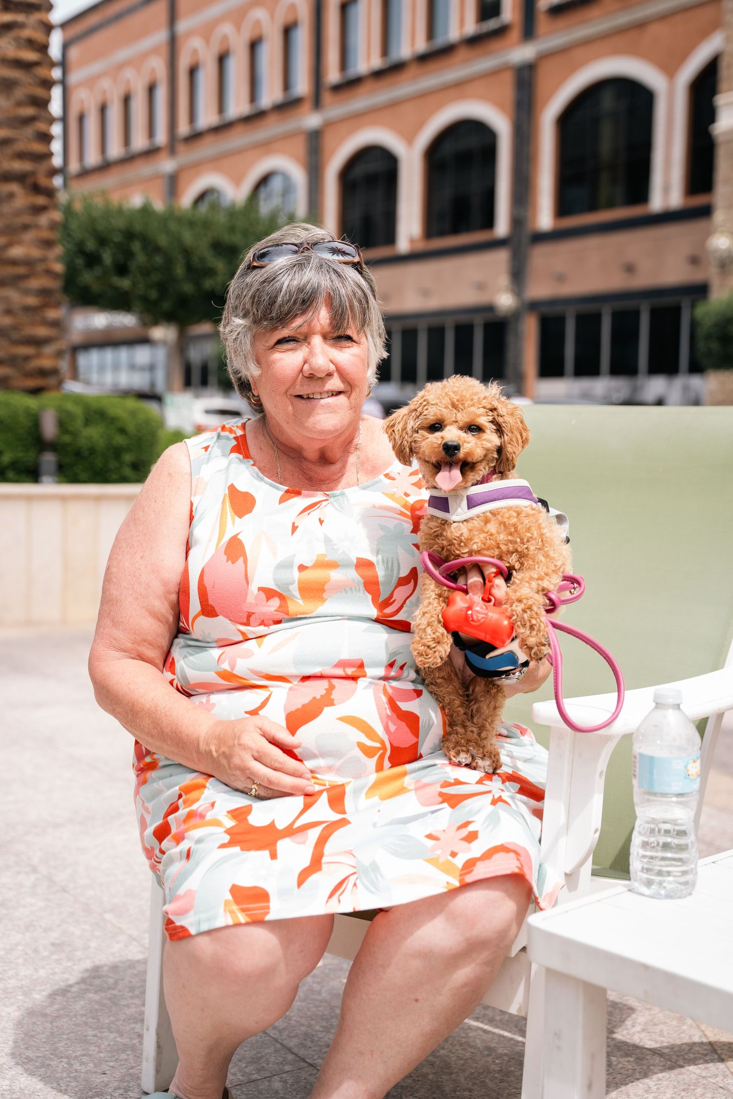 Happy attendee sitting outdoors with small brown dog wearing matching outfits.