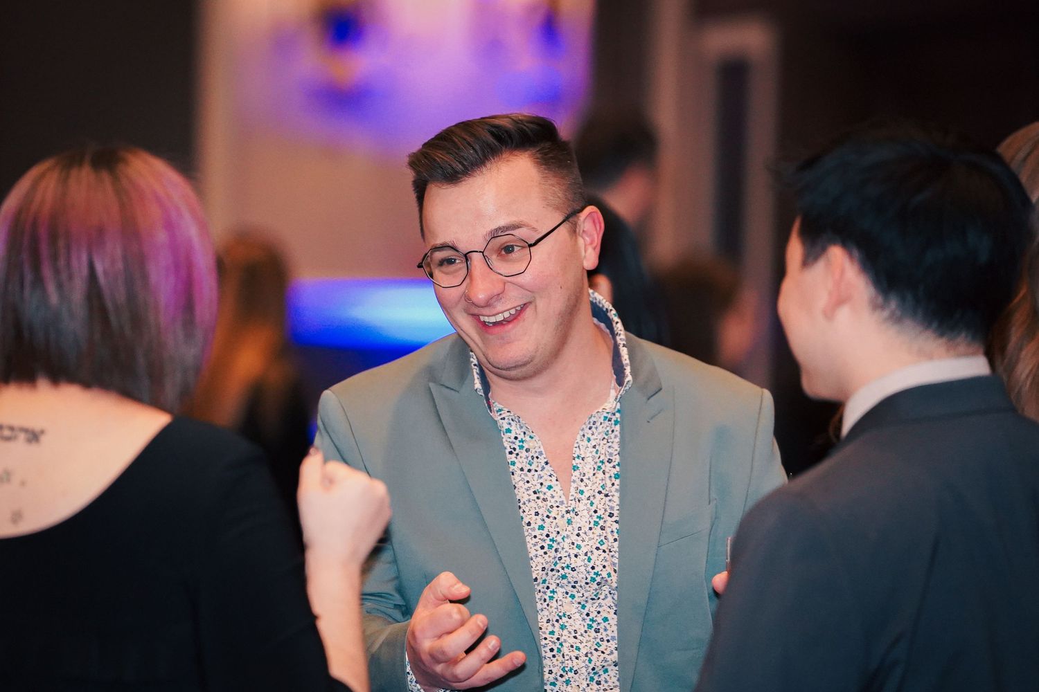 Professional networking conversation at formal evening event with blue accent lighting.