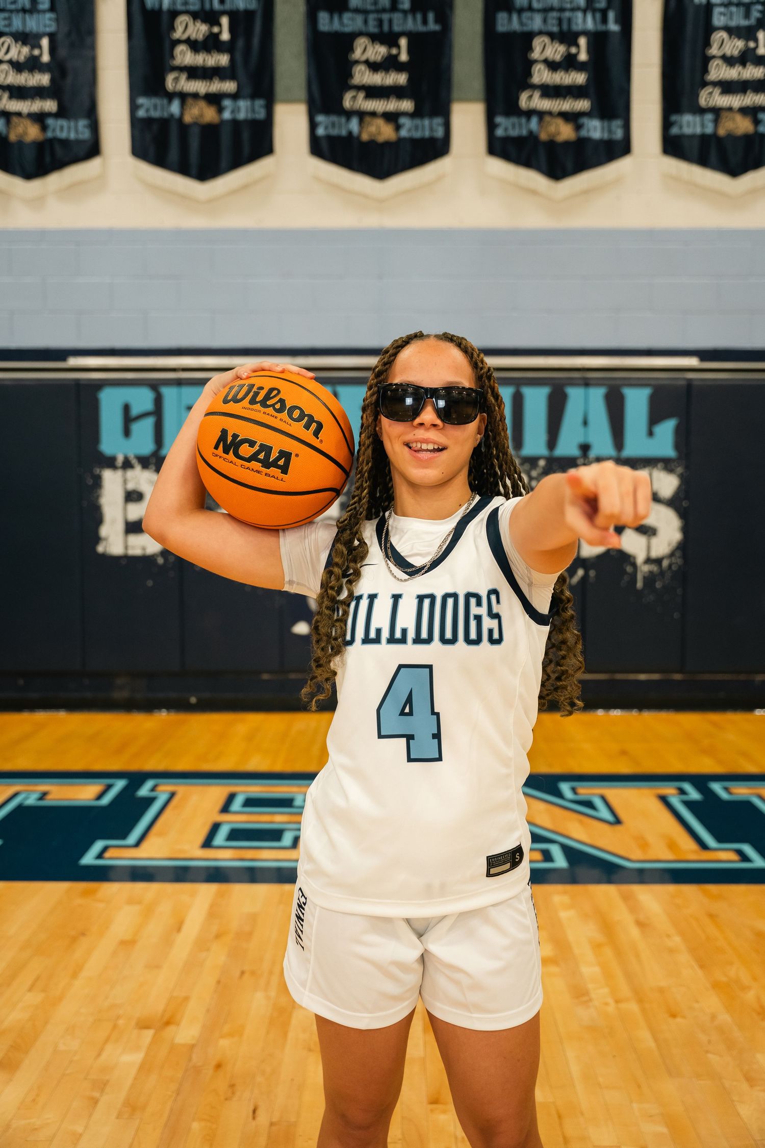 Basketball player wearing sunglasses and number 4 jersey poses with Wilson NCAA basketball.