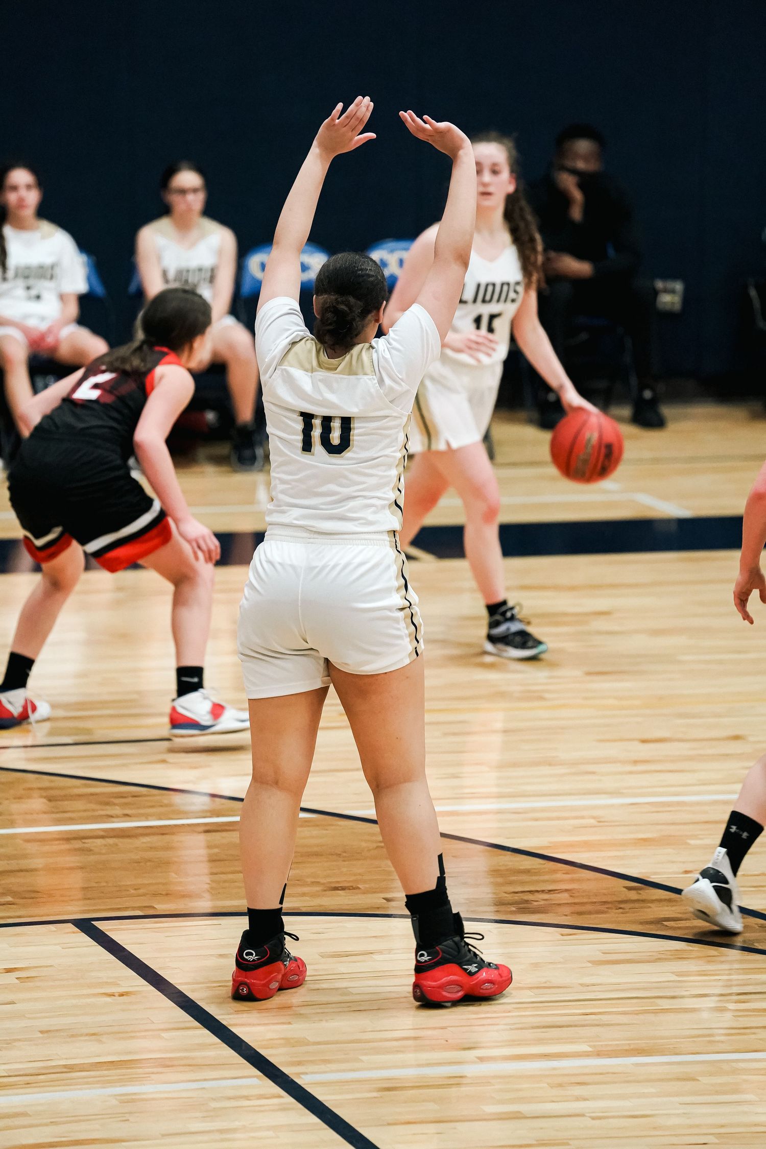 Basketball players in white uniforms focusing on defense drills during practice.