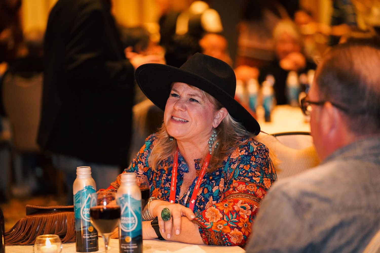 Event attendees socializing and enjoying drinks at tables during an evening gathering.