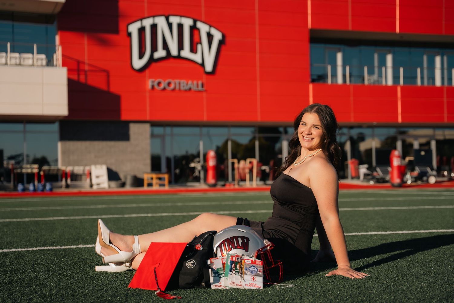UNLV campus building with red exterior serves as backdrop for graduation photos.