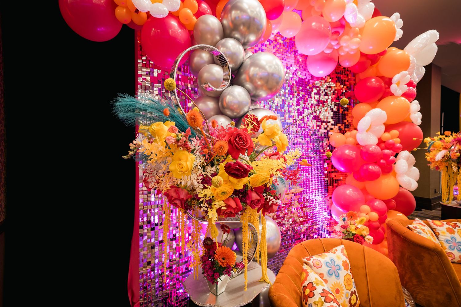 Vibrant balloon arch installation with pink and orange hues and twinkling fairy lights.