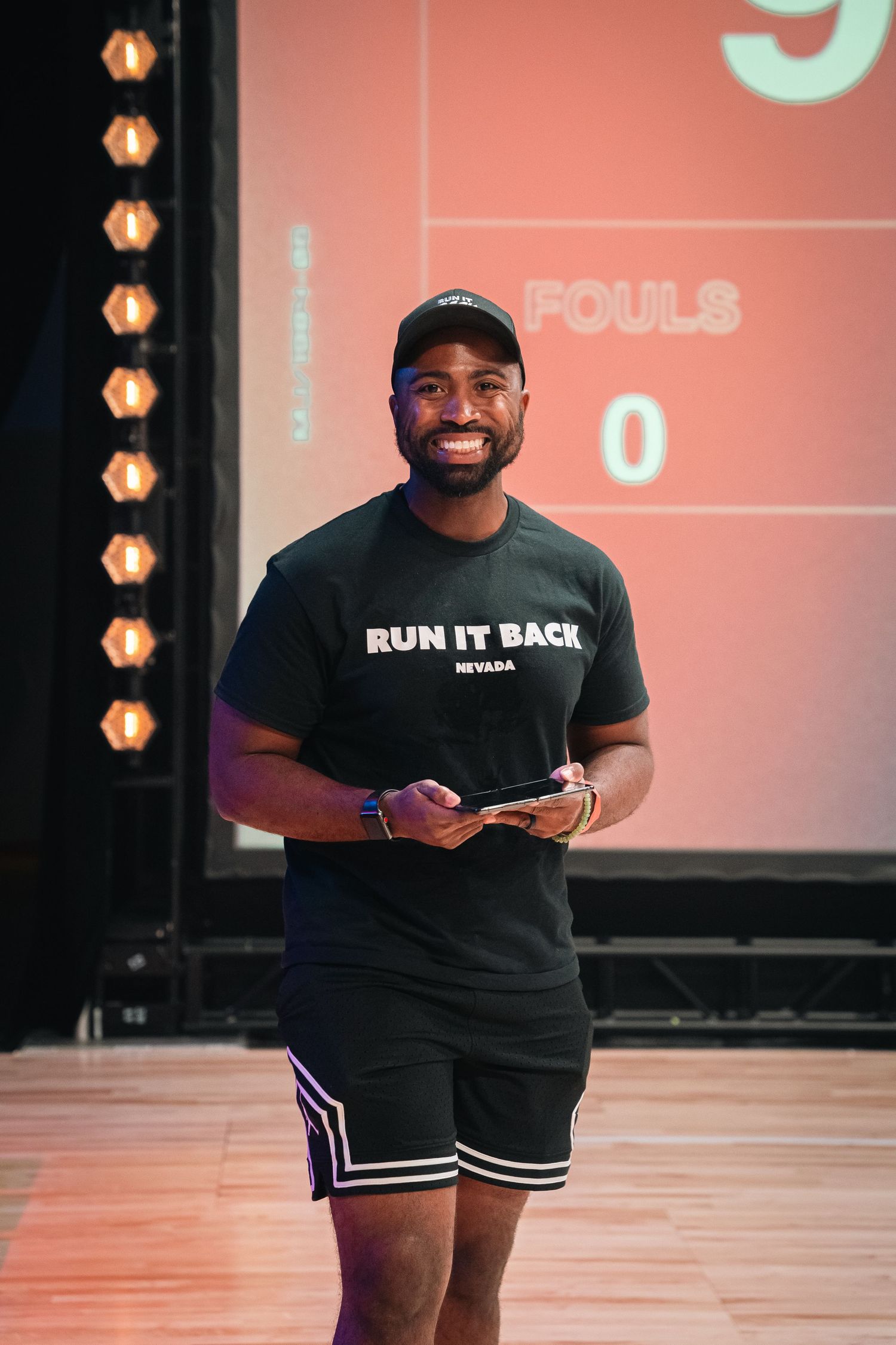 Instructors wearing black 'Run It Back' t-shirts leading a basketball training session.