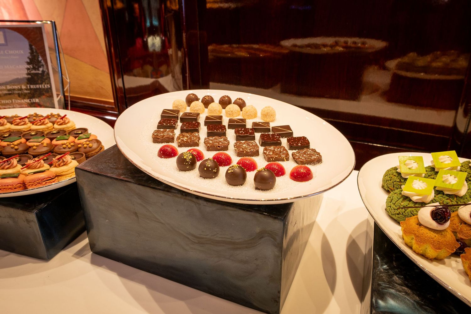 Assorted chocolate truffles and desserts arranged on white platters at a catering display.