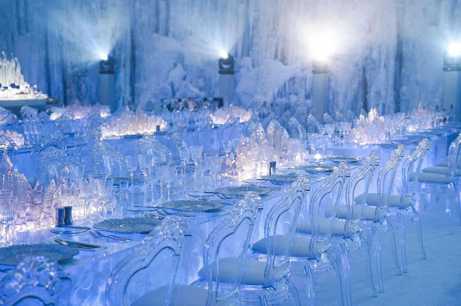 Elegant ice-themed reception setup with transparent chairs and blue lighting effects.