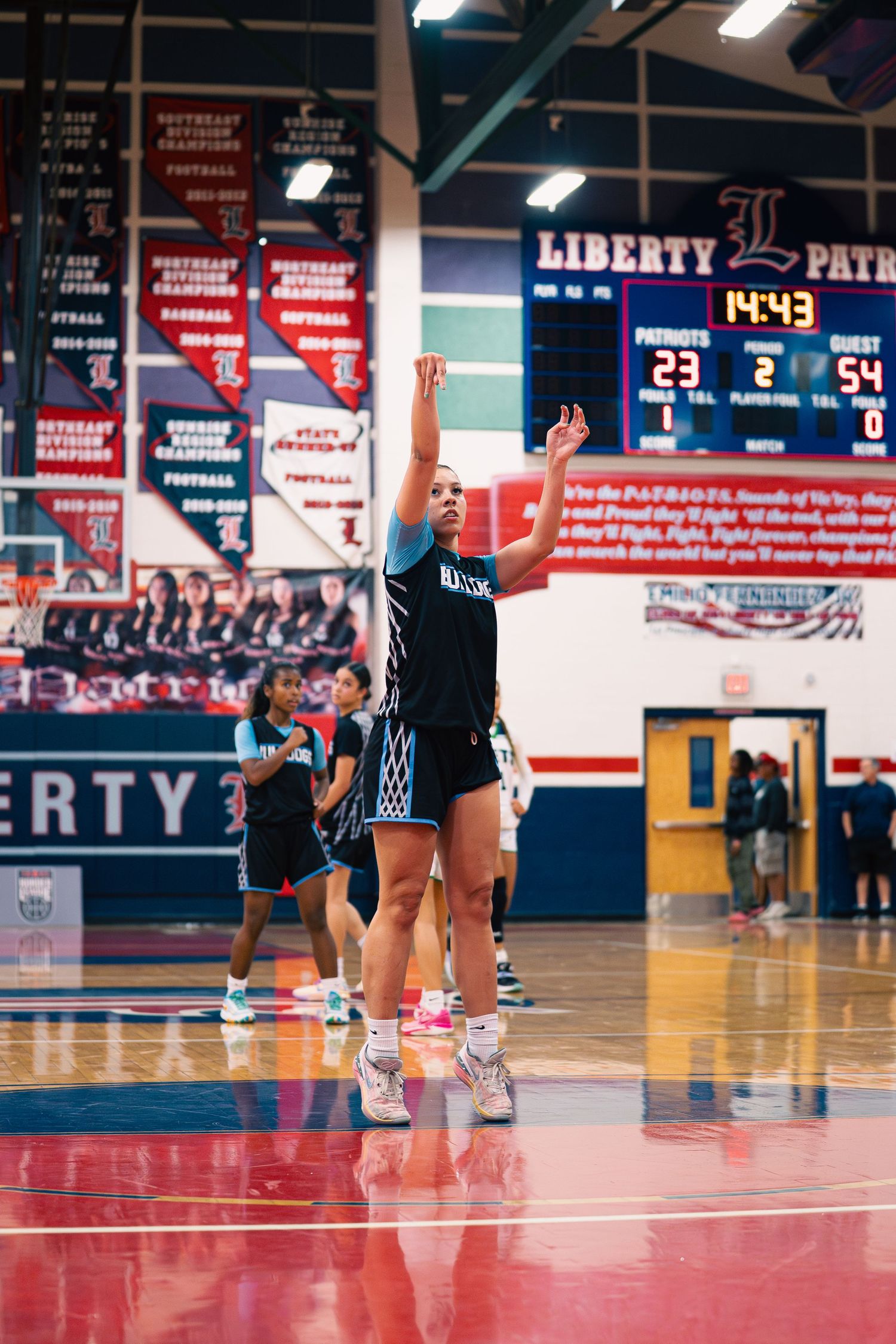 Basketball player takes a jump shot during warmups at Liberty Patriots gymnasium.