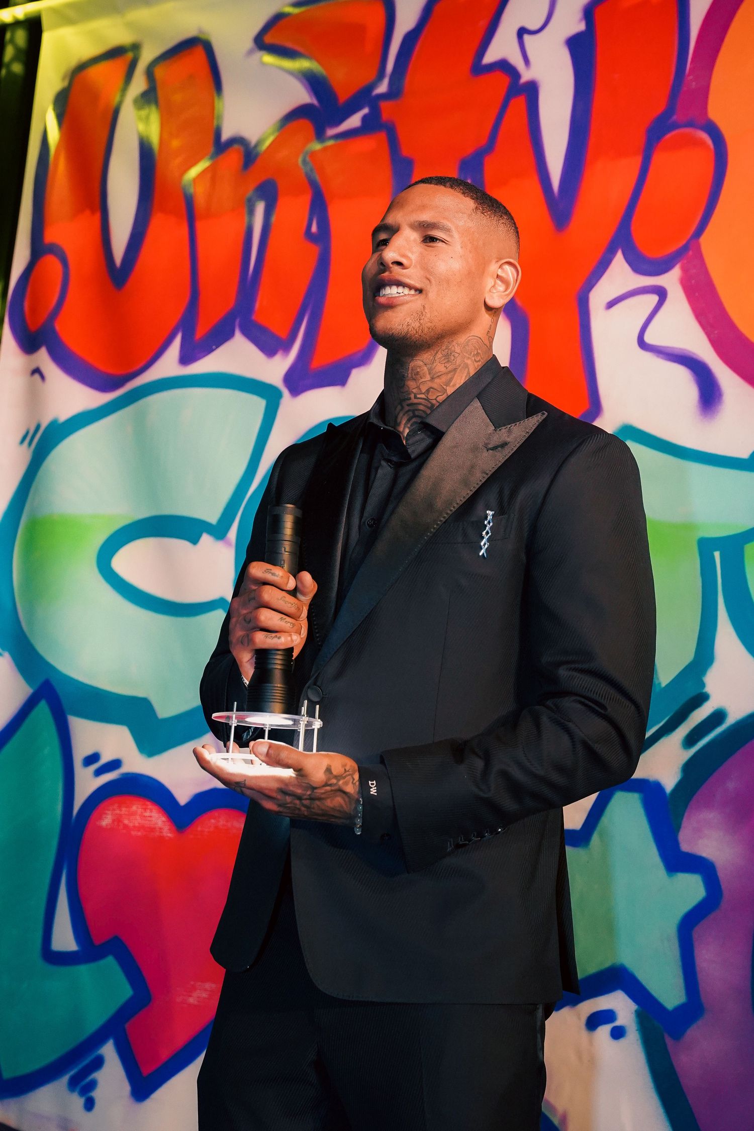 Speaker presenting in front of colorful graffiti-style backdrop at professional event.