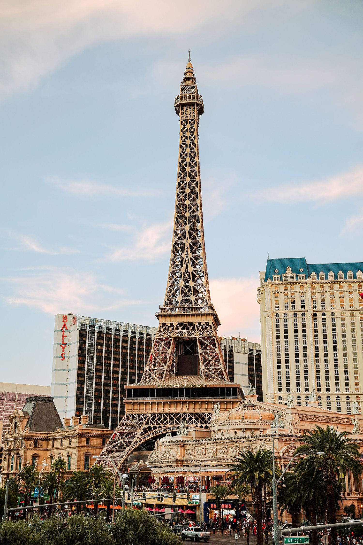 Eiffel Tower replica with palm trees at Paris Las Vegas resort against blue sky.