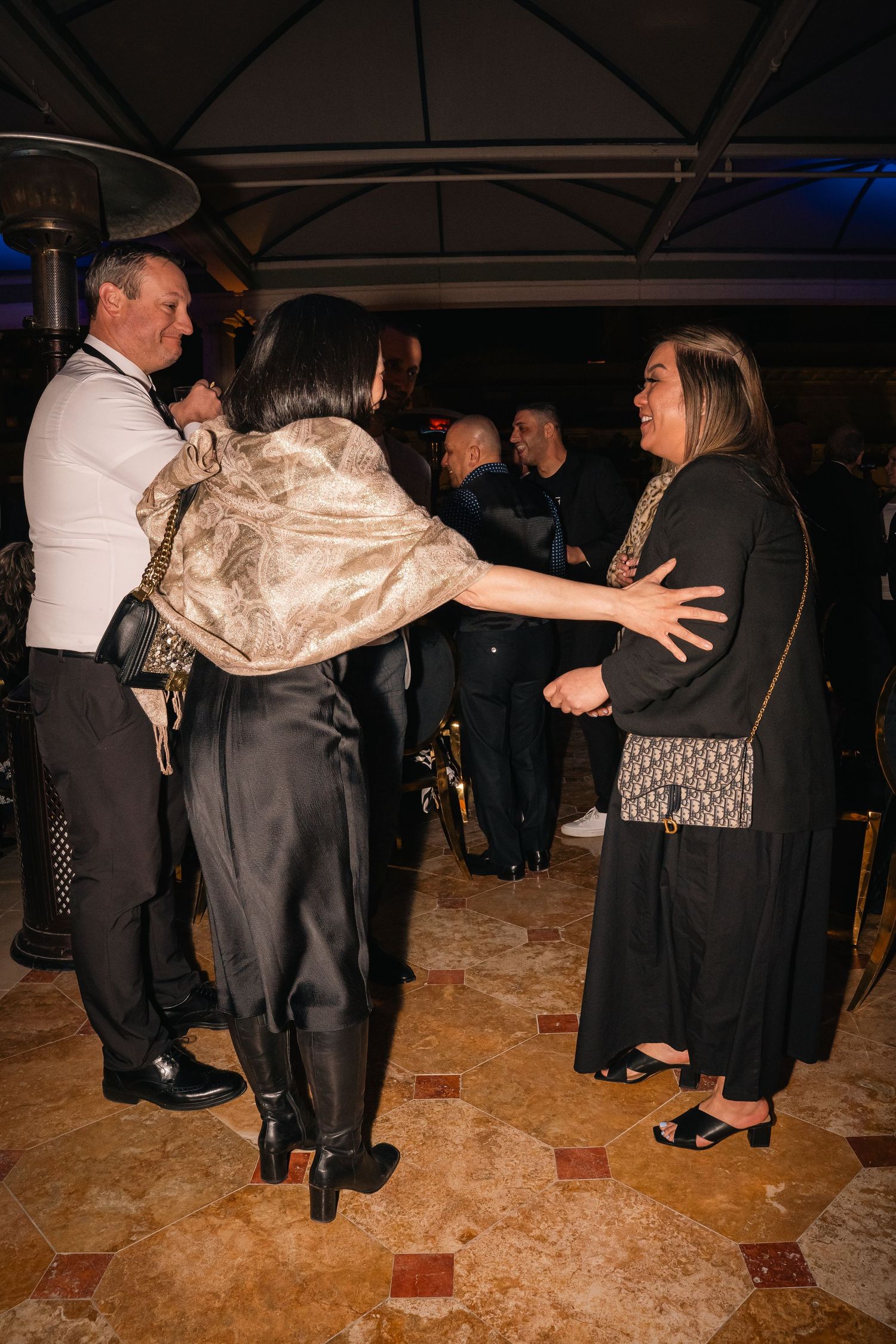 Group of attendees socializing and gesturing animatedly at an evening business function.