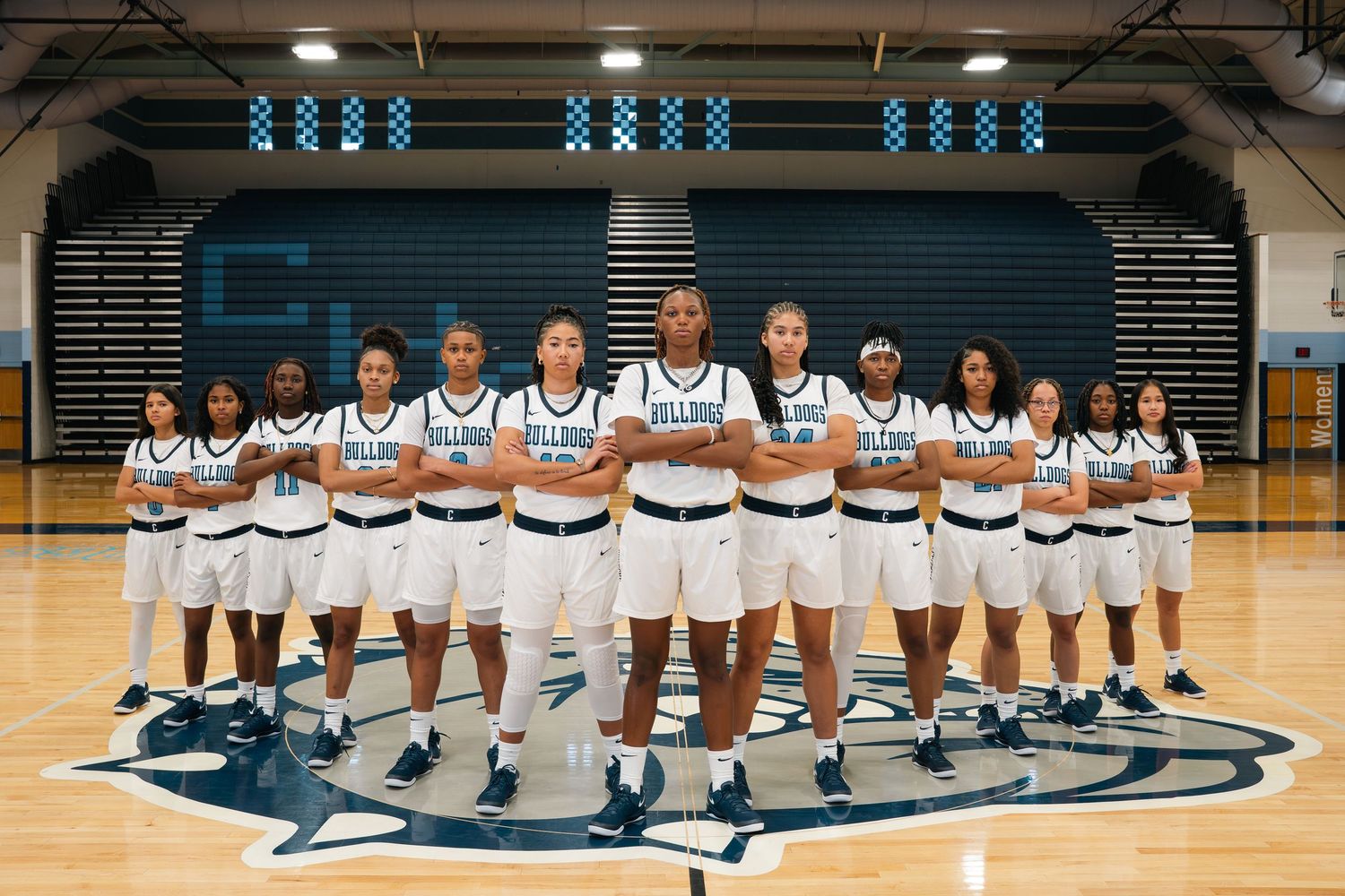 Basketball team photo in white uniforms lined up on home court.