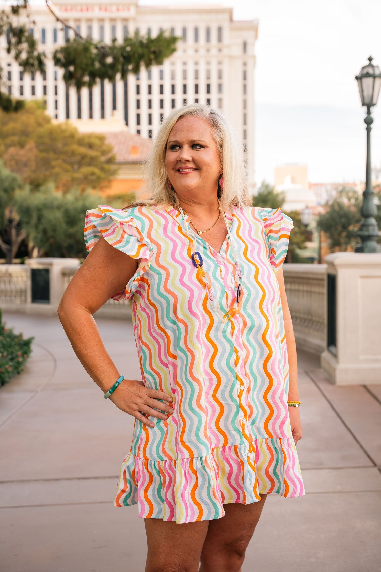 Colorful wavy striped top shown in outdoor urban setting with buildings and lamp posts visible.