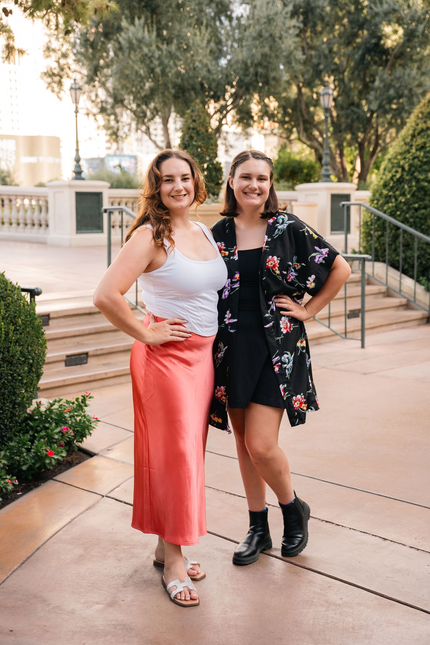 Two friends in contrasting outfits pose together on a resort walkway.