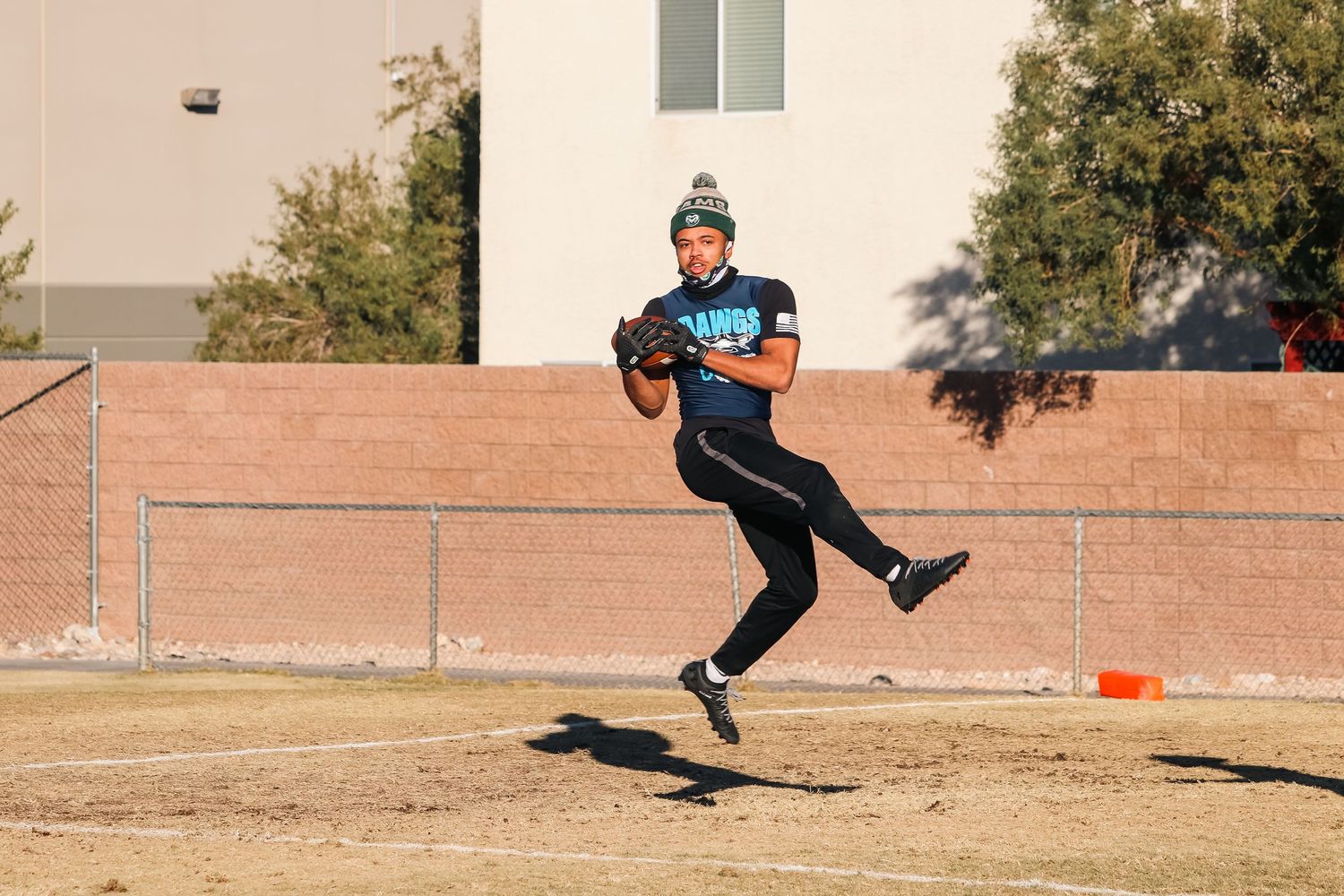 Athlete jumping while practicing football throwing technique on outdoor field.