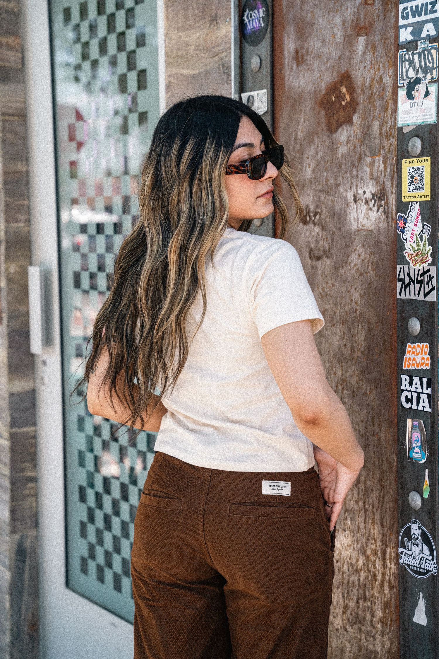Side profile fashion shot against urban wall with vintage inspired outfit and sunglasses.