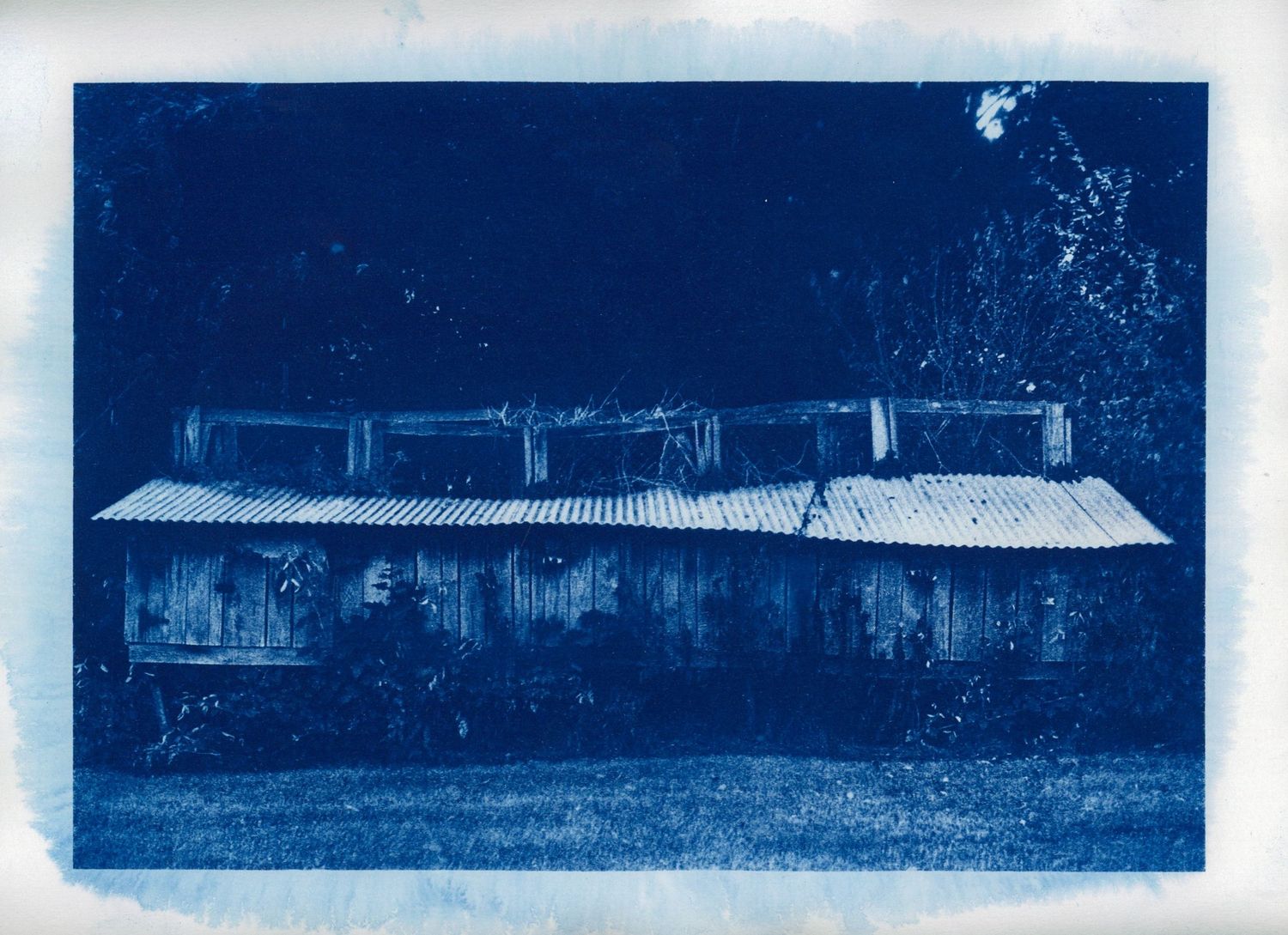 Long rustic building photographed in monochromatic blue tones.
