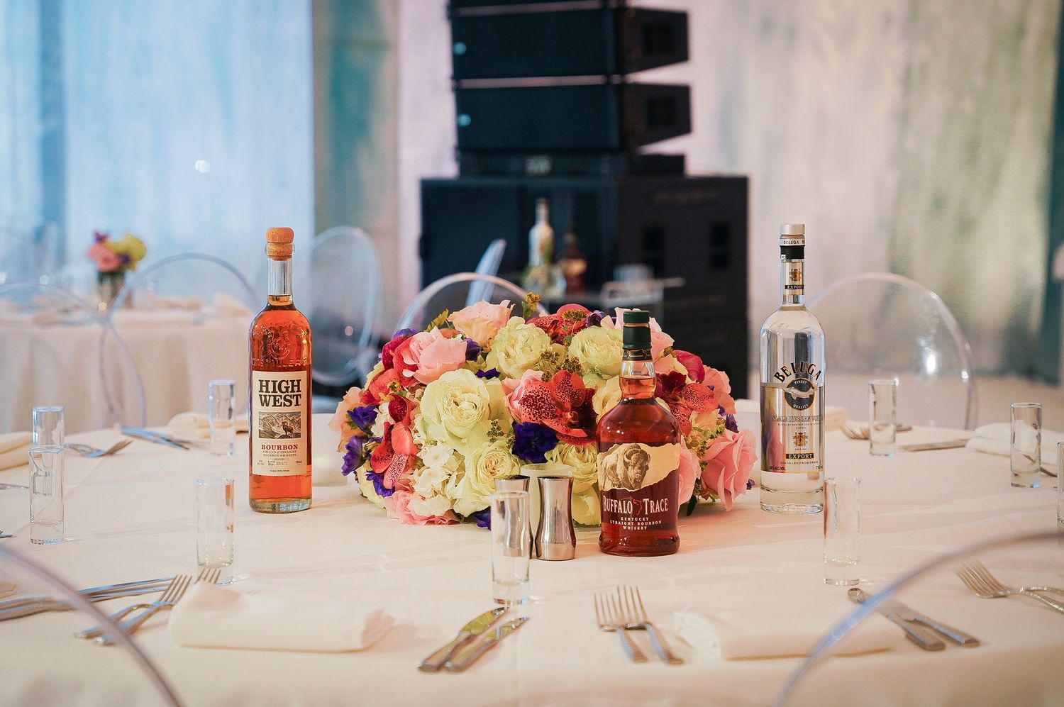Elegant table setting with pink floral centerpiece and liquor bottles.