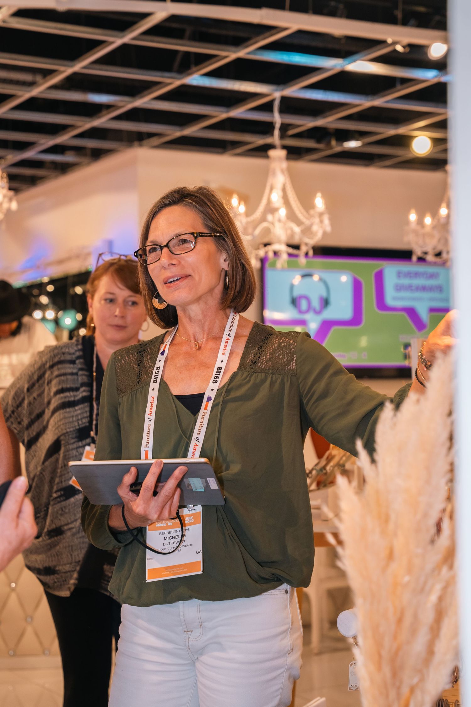 A person using a tablet helps with retail operations under elegant chandelier lighting.
