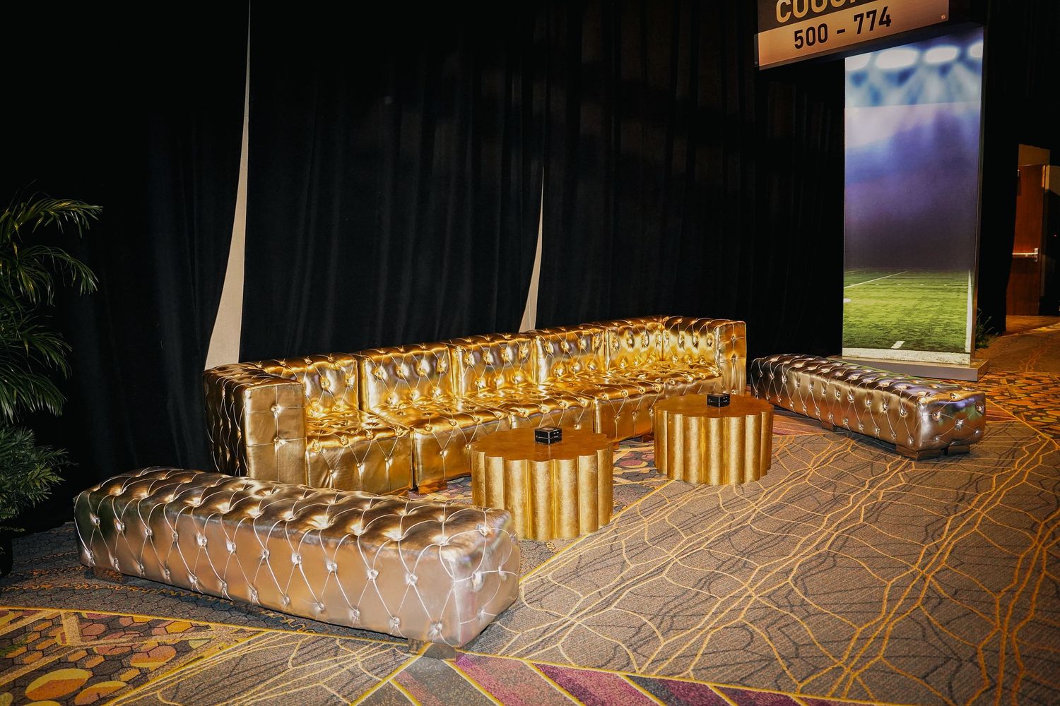 Event space with golden decorative elements and uplighting creating an elegant atmosphere.